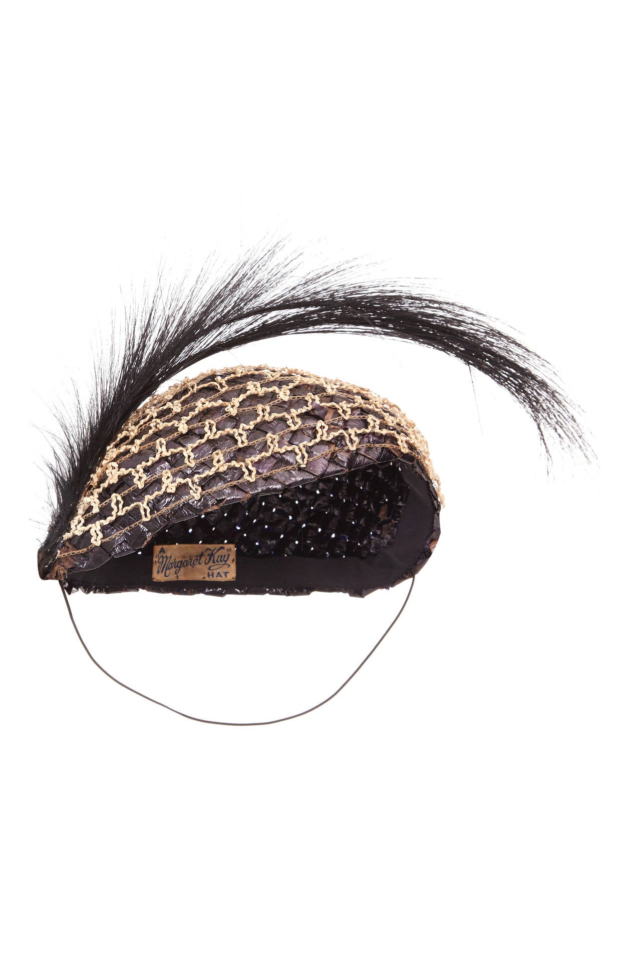 Very rare, original 1920s flapper hat made from coated black woven raffia. Additional antique two-tone cream lattice overlay to one half of the hat, topped with a black hair spray.  Original label reads 