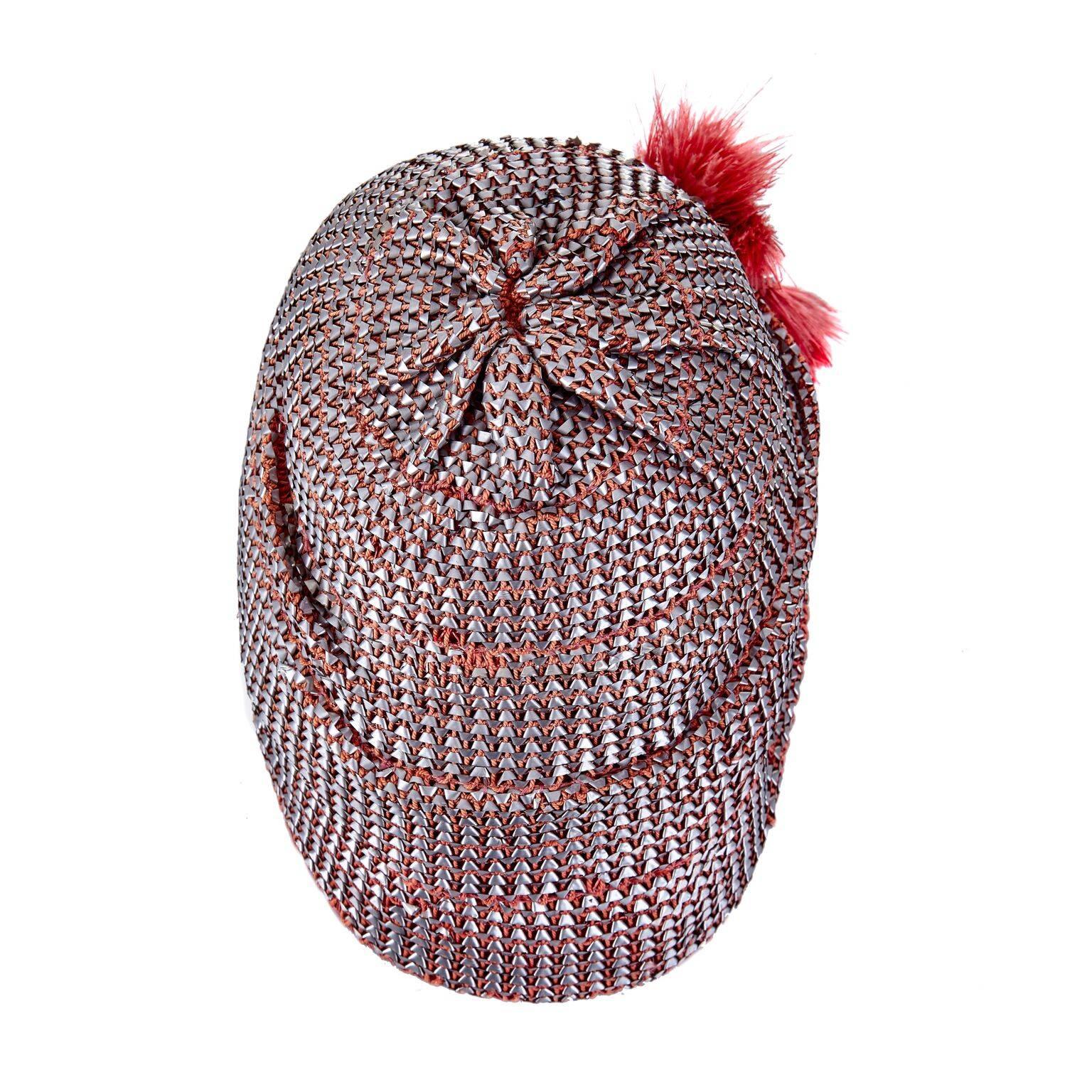 Dieser exquisite Flapper-Cloche-Hut aus den 1920er Jahren mit metallischem Bastgeflecht ist in ausgezeichnetem Vintage-Zustand. Der Hut ist aus weichem, rotem Filz geformt und innen mit einem grobkörnigen Band versehen, so dass der Hut beim Tragen
