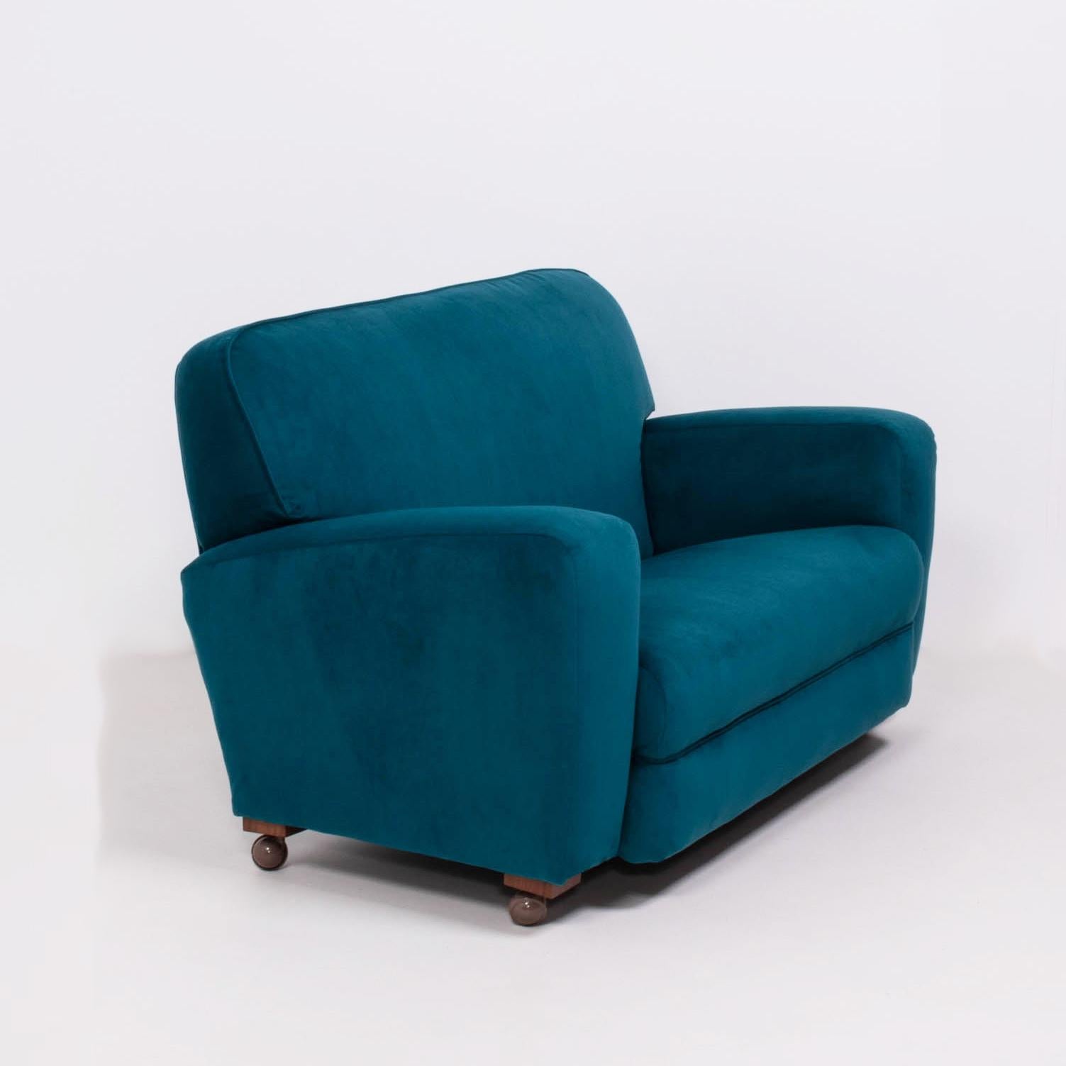 This is an original 1930s Art Deco curved 2-seat sofa.

Newly reupholstered in plush blue teal velvet, the sofa features wide armrests and high, comfortable backs.

The blocks and castor wheels have been replaced on all of the