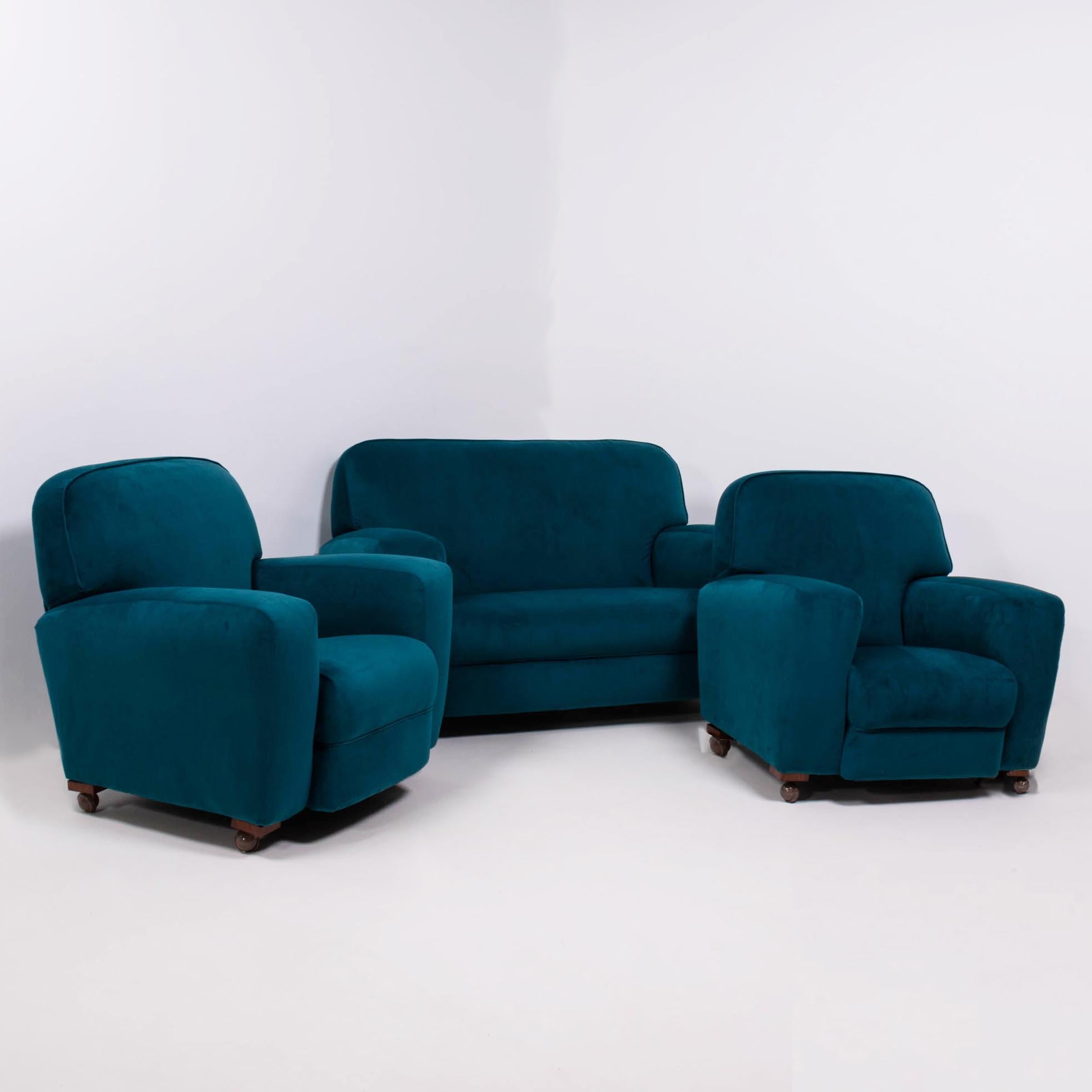 This original 1930s Art Deco suite is comprised of a curved 2-seat sofa and matching pair of armchairs, offering a full seating arrangement in a rare set.

Newly reupholstered in plush blue teal velvet, all three pieces feature wide armrests and