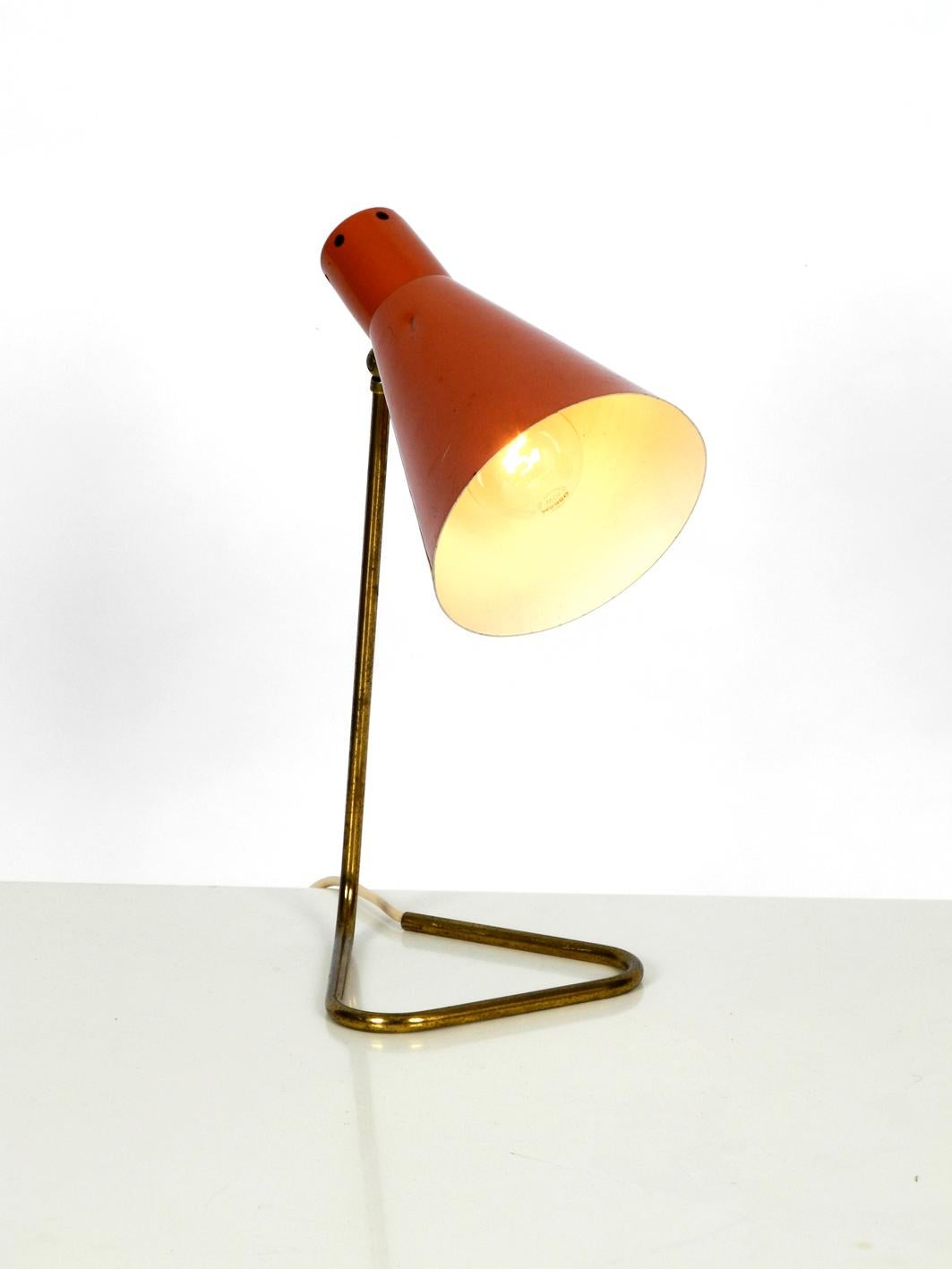 Beautiful original 1950s table lamp from Italy.
Foot and neck of a curved brass tube, with cable routing. Lampshade is painted with brick red paint. Very nice typical minimalist midcentury design with a fantastic patina. Good vintage condition.
