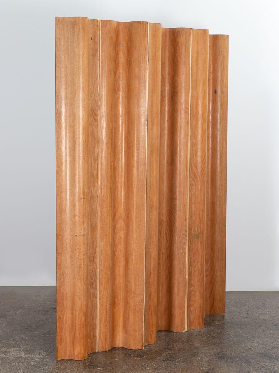 An early molded plywood screen divider in calico ash, designed by Charles & Ray Eames, manufactured by Herman Miller. The screen's ingenious design allows it to be formed into a variety of appealing shapes. Cotton canvas hinges are flexible,