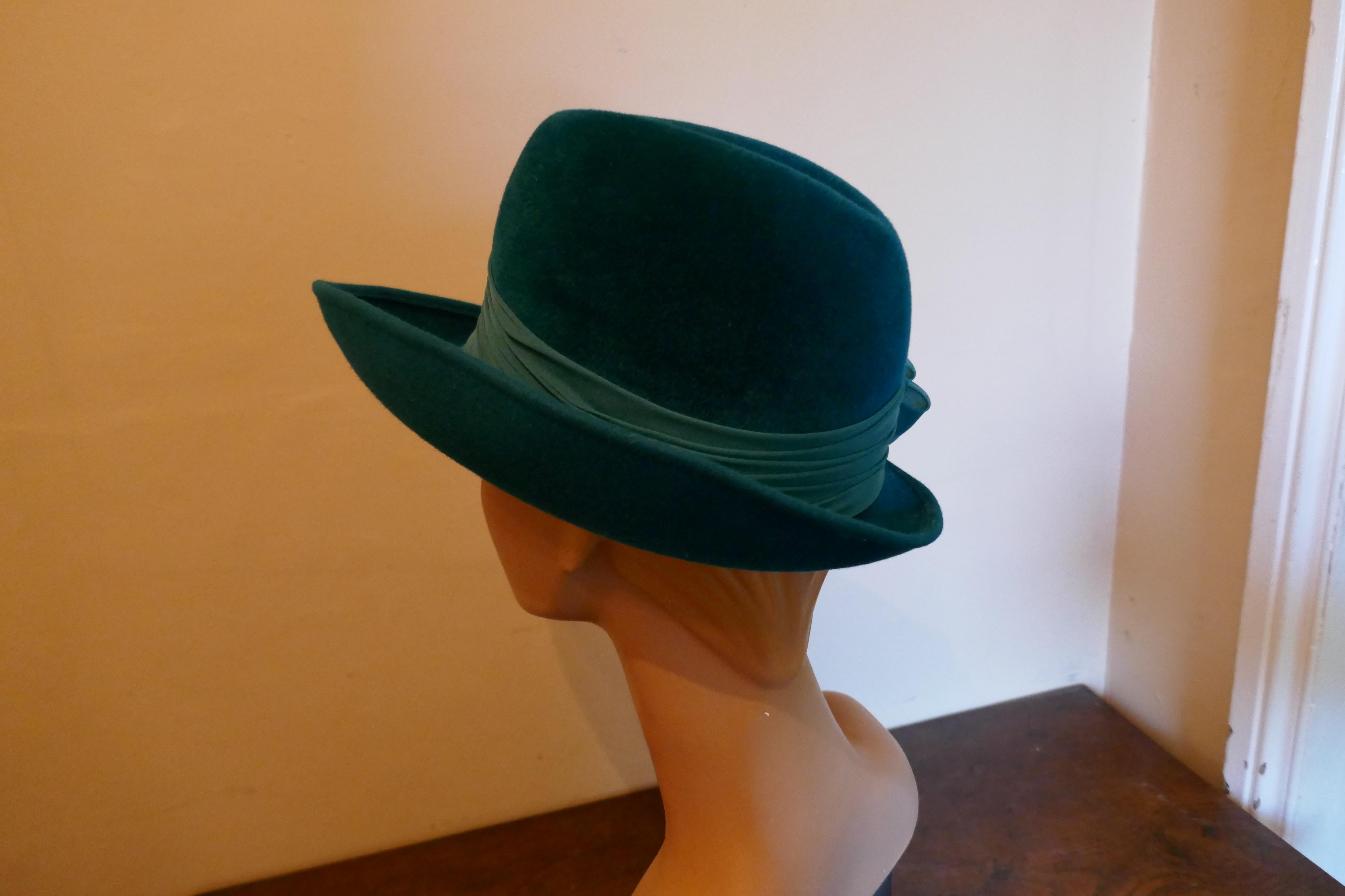 Original 1960s Jaunty Teal Fedora Style Hat 

This gorgeous Hat is made in fur Felt, it has a wide chiffon gathered band tied at one side in a big bow and a stitched brim
This one is an exquisite design wear it anywhere and be noticed
The hat