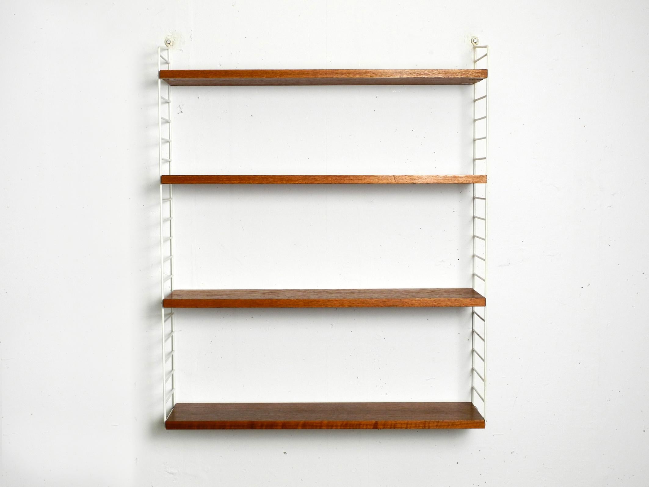 Original 1960s Nisse Strinning wall hanging shelf with four solid wood shelves with teak veneer.
2 metal ladders with plastic coating in white.
Both ladders are in good condition. No rust. The plastic coating is still good.
Good vintage condition.