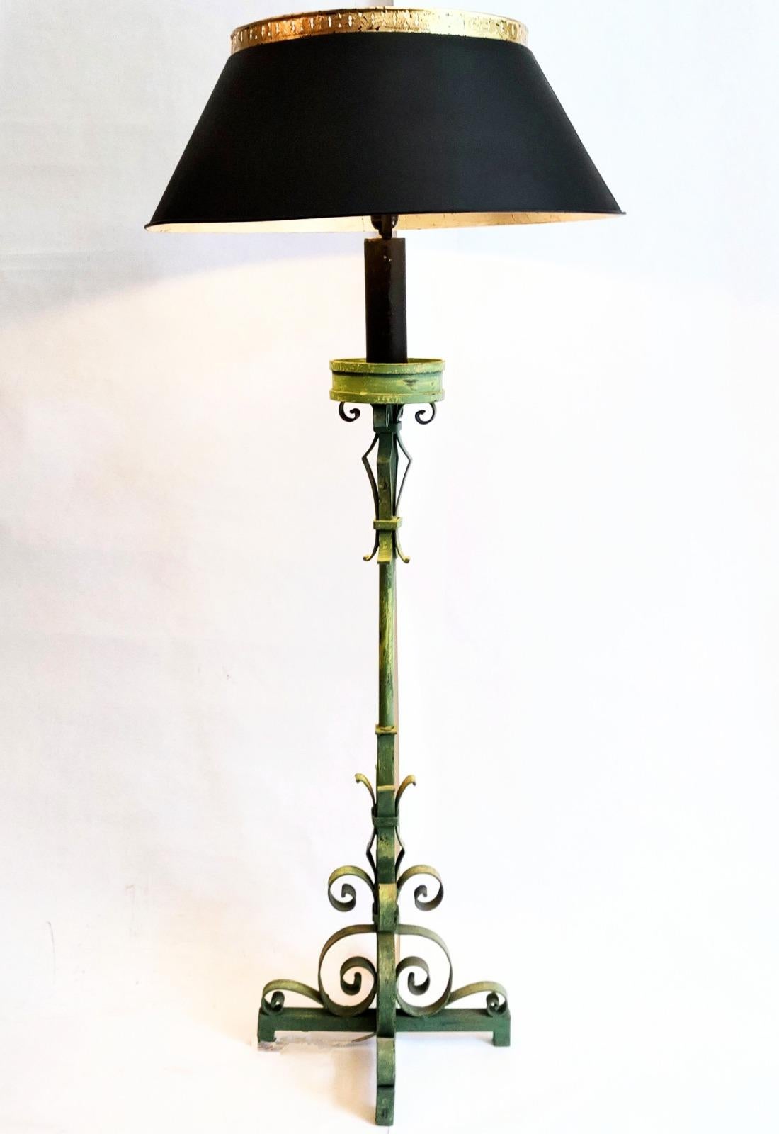 Wrought iron floor lamp with intricated hand-forged forms on a base with four sturdy legs. Keeps its original cactus-green color with a natural patina and signs of use and wear. Comes with a large metallic lampshade recently painted matte black on