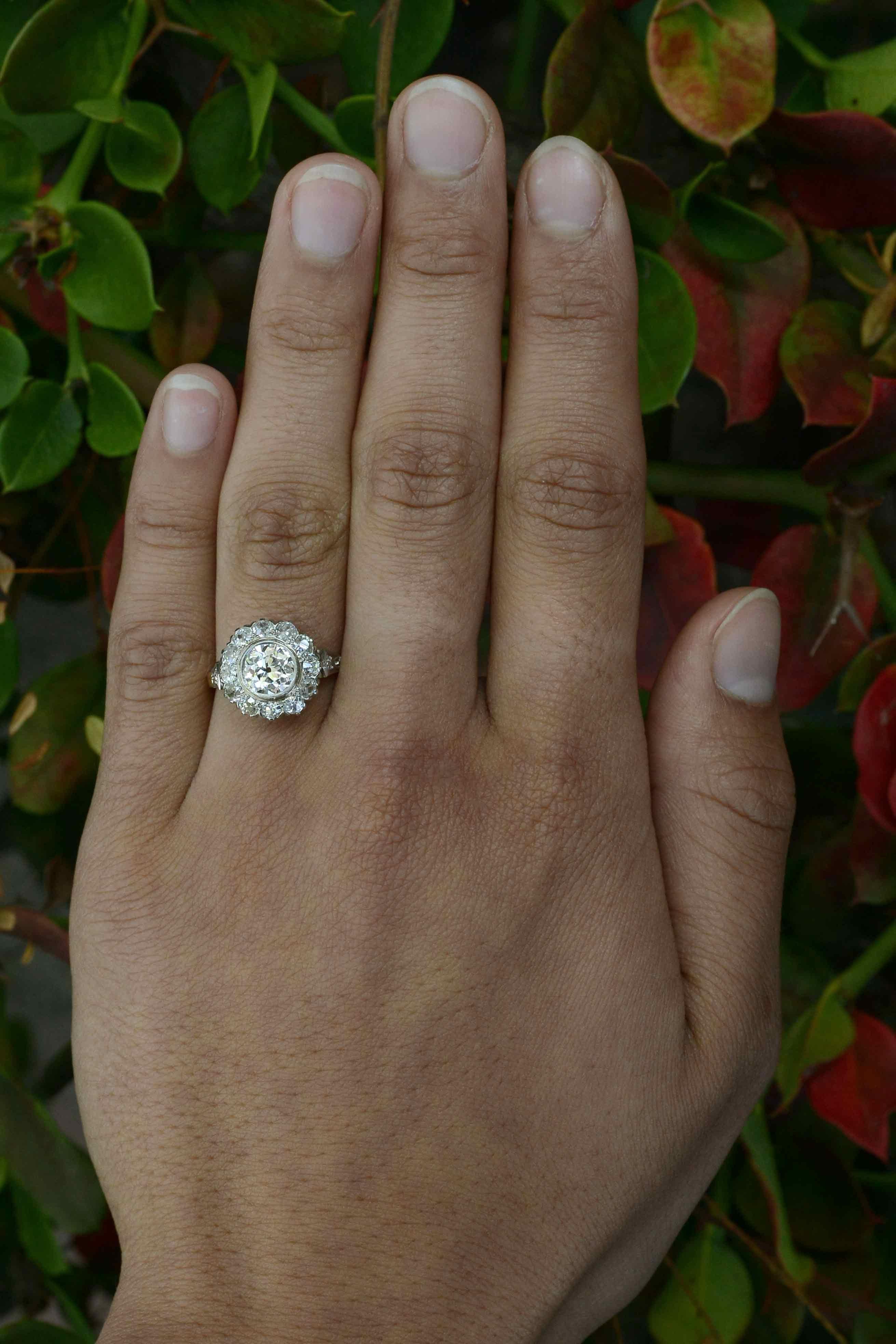 This stunning, original Edwardian style diamond cluster engagement ring centers on a captivating brilliant antique old mine-cut diamond. Weighing 1.14 carat, it scintillates from the center of a sparkling halo of 12 old mine-cut diamonds, bringing