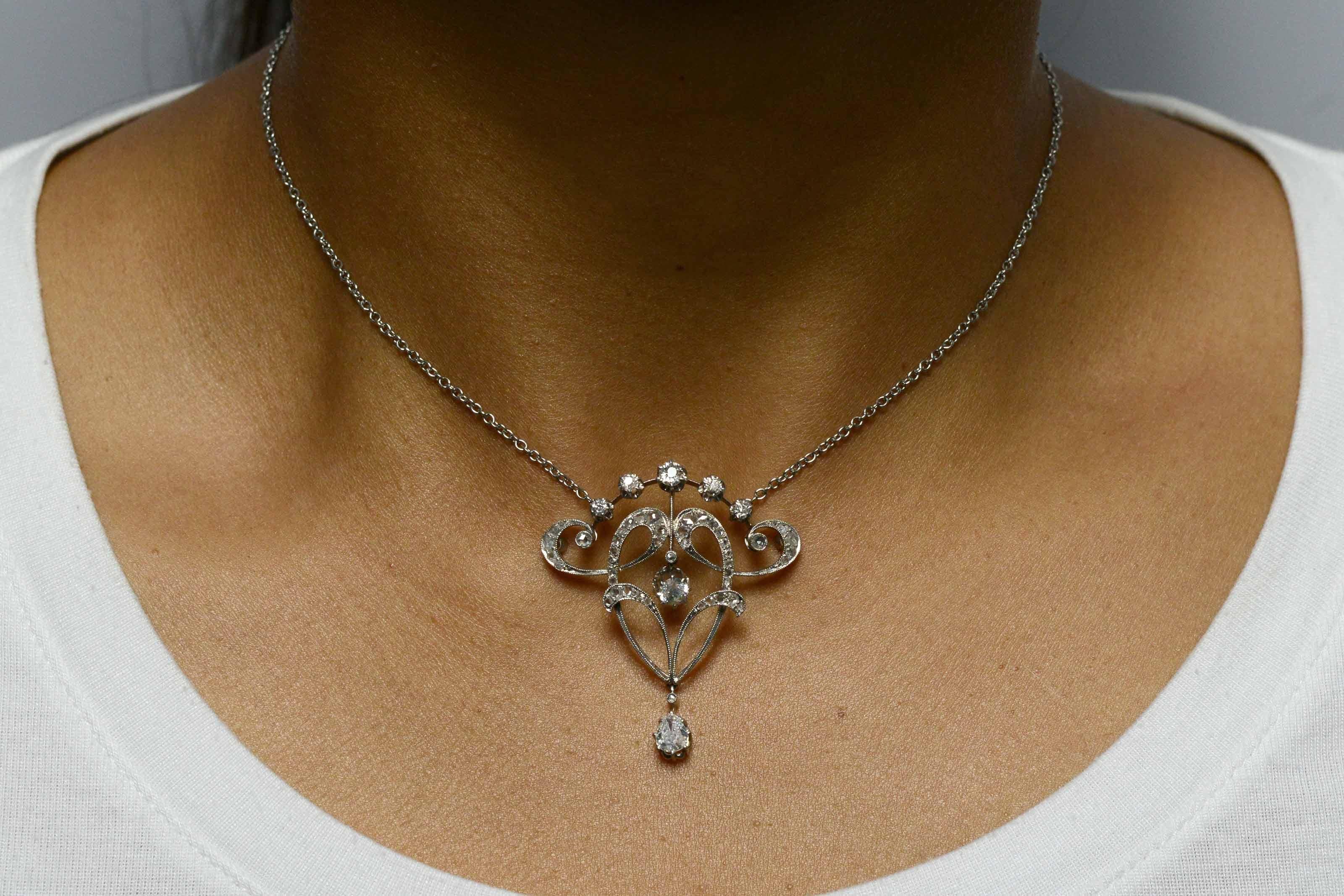 An intriguing antique Edwardian diamond necklace pendant finely handcrafted of platinum with enchanting, swirling foliate swags and garlands, typical of the French Belle Epoque era. Adorned with over 1 carat of twinkling old mine and rose cut