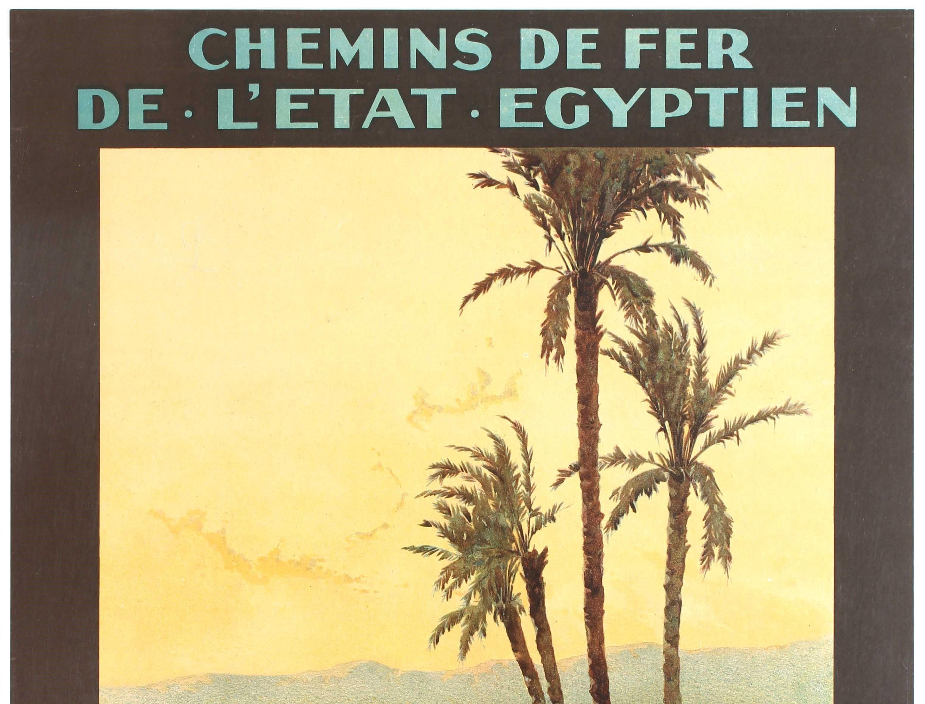 Original antique travel poster advertising winter in Aswan issued by the Egyptian State Railway featuring a great image by Augustus Osborne Lamplough (1877-1930) of people on the river bank below palm trees with traditional sailing boats (felucca)