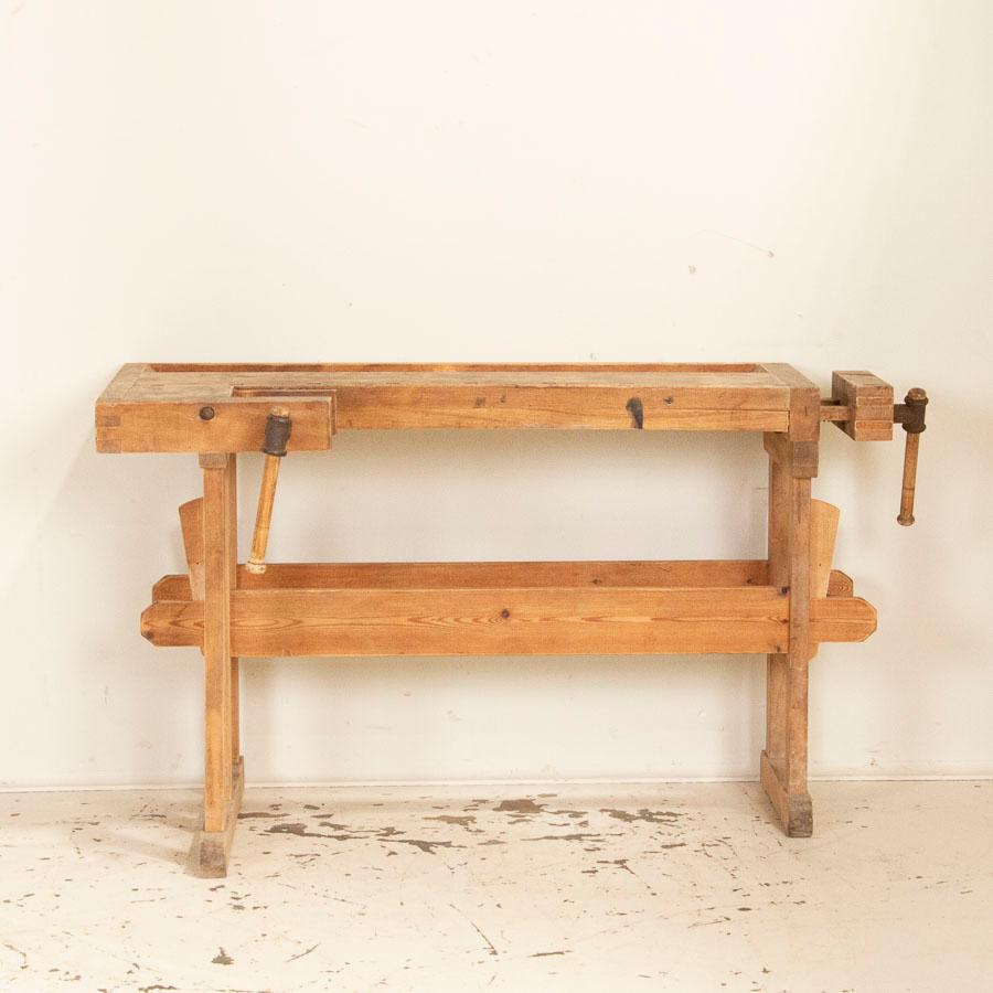This wonderful old antique carpenters' workbench is unique due to its smaller size, making it user friendly for a variety of uses. The darker color, scratches and dings of the top reveal the years of work done upon it, which adds to the vintage