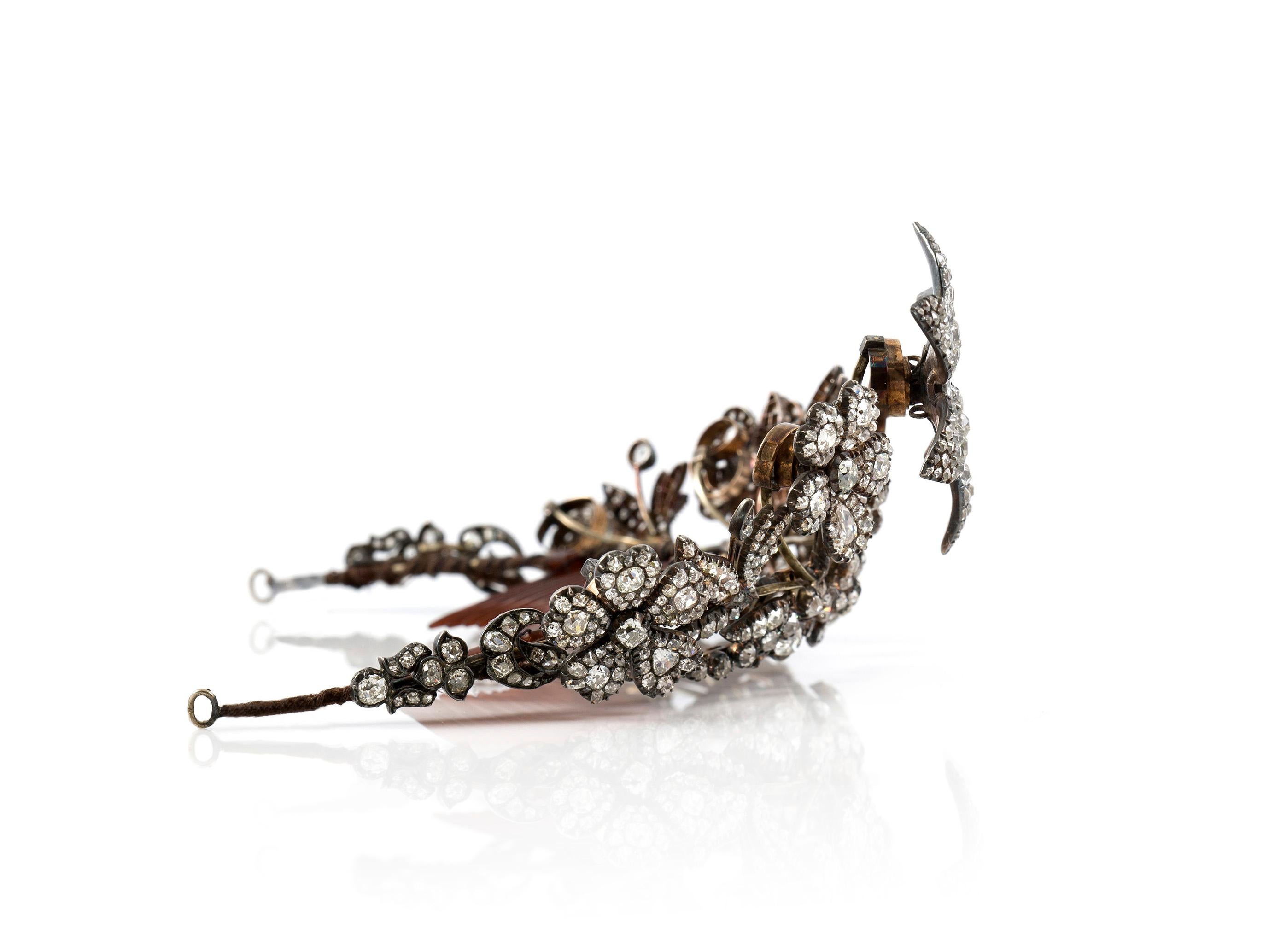 Antique Tiara finely crafted in silver and gold with central six-petal flower head, with cushion shaped old-cut diamonds, to the similarly-set tapering scrolling floral and foliate surround, with further entwined bud and flower head highlights.