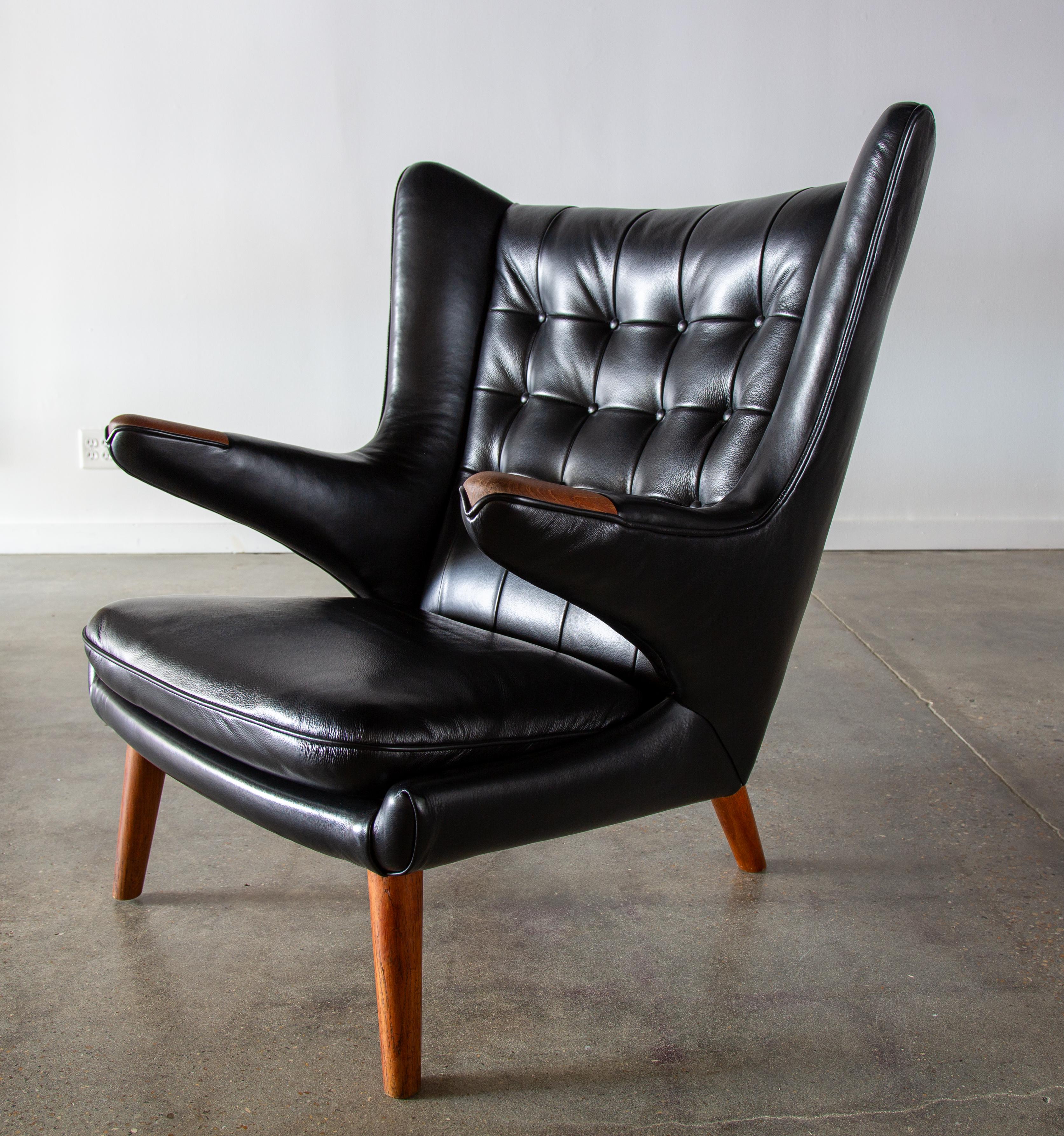 An original AP19 “Papa bear” chair designed by Hans J. Wegner for A.P. Stolen, designed in 1951 and made in Denmark.  This example with new black leather and featuring oak legs and teak paws. Retaining its original made in Denmark medallion. This