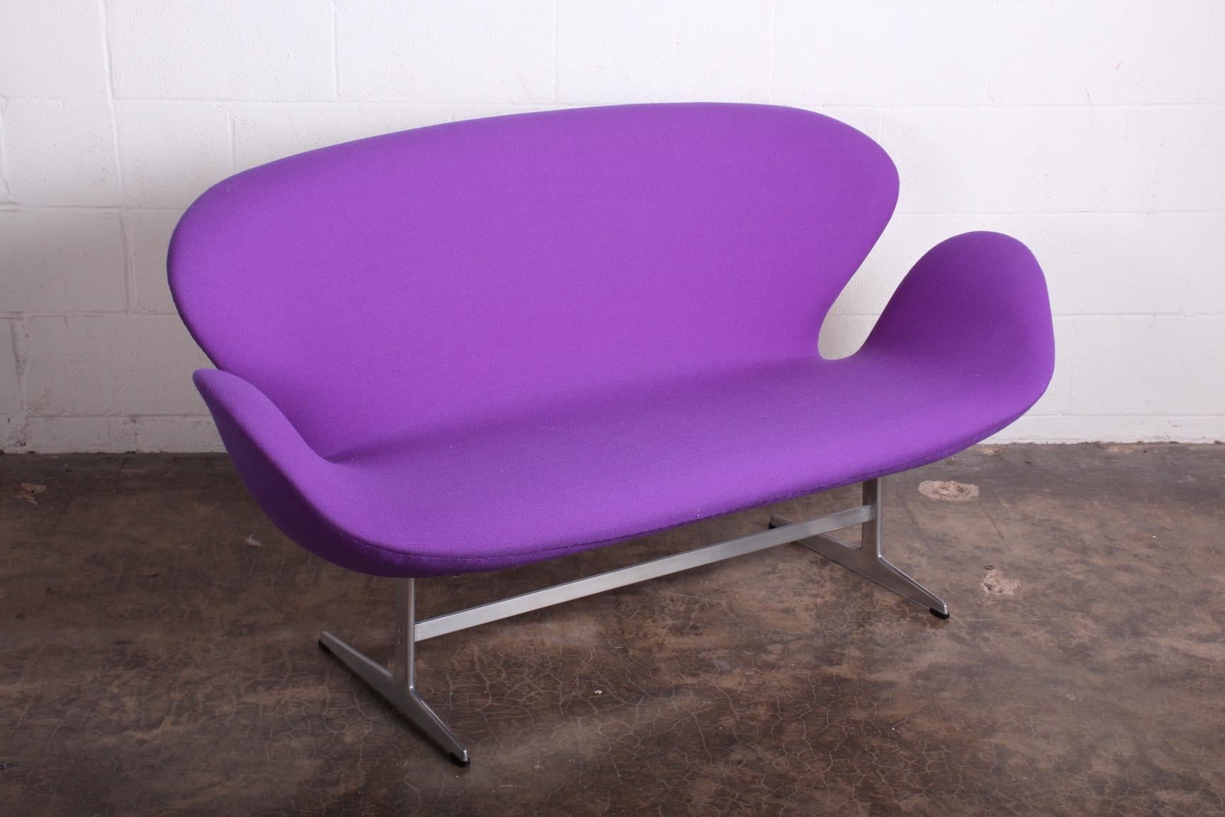 An original Swan settee, sofa, bench designed by Arne Jacobsen for Fritz Hansen. The purple fabric is an older restoration in very good condition.