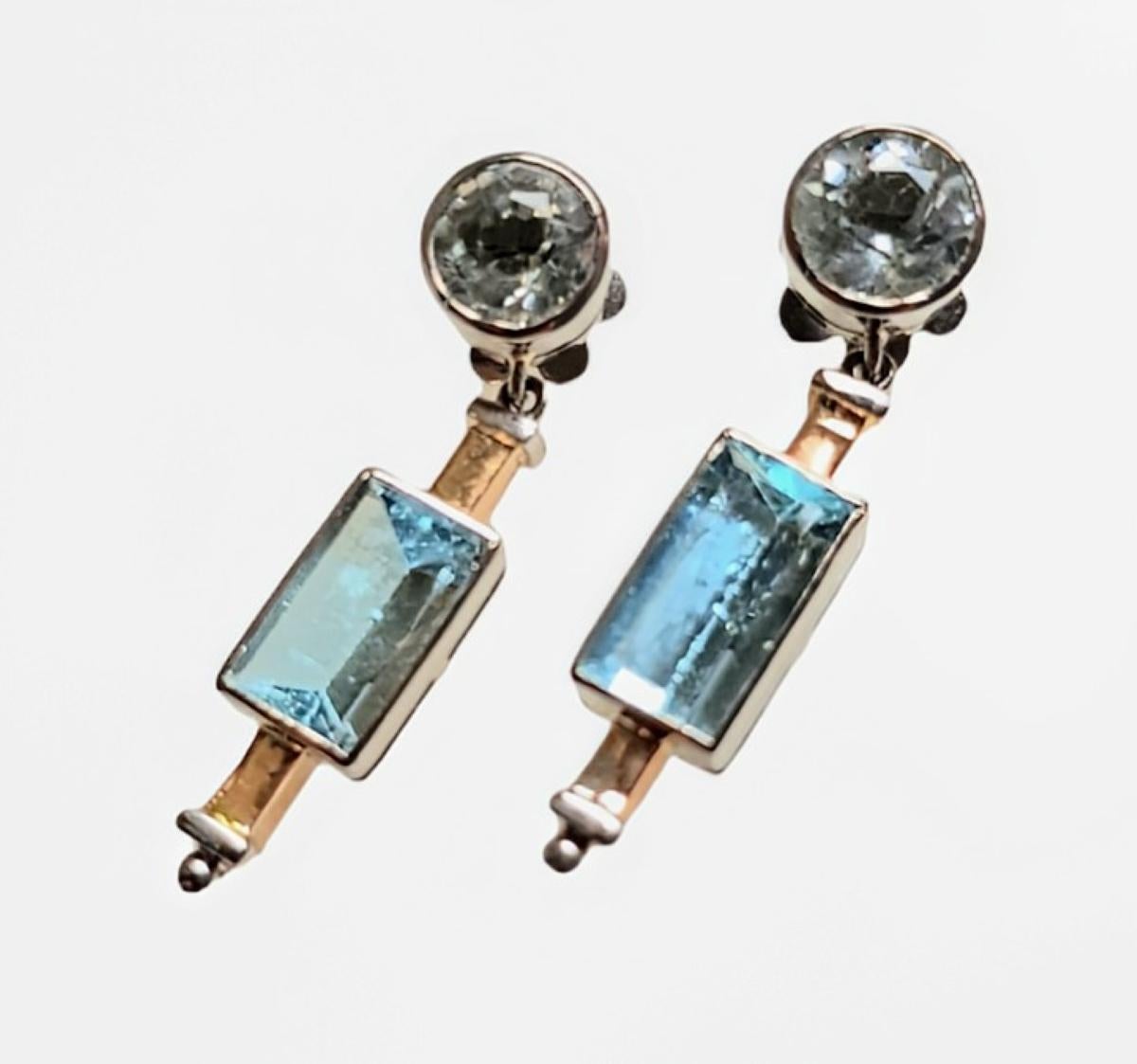Boucles d'oreilles pendantes en aigue-marine Art Déco, Circa 1925
Ces exquises boucles d'oreilles pendantes sont un exemple classique de l'artisanat Art déco, mettant en valeur des lignes épurées, la symétrie et l'élégance géométrique. Chaque boucle