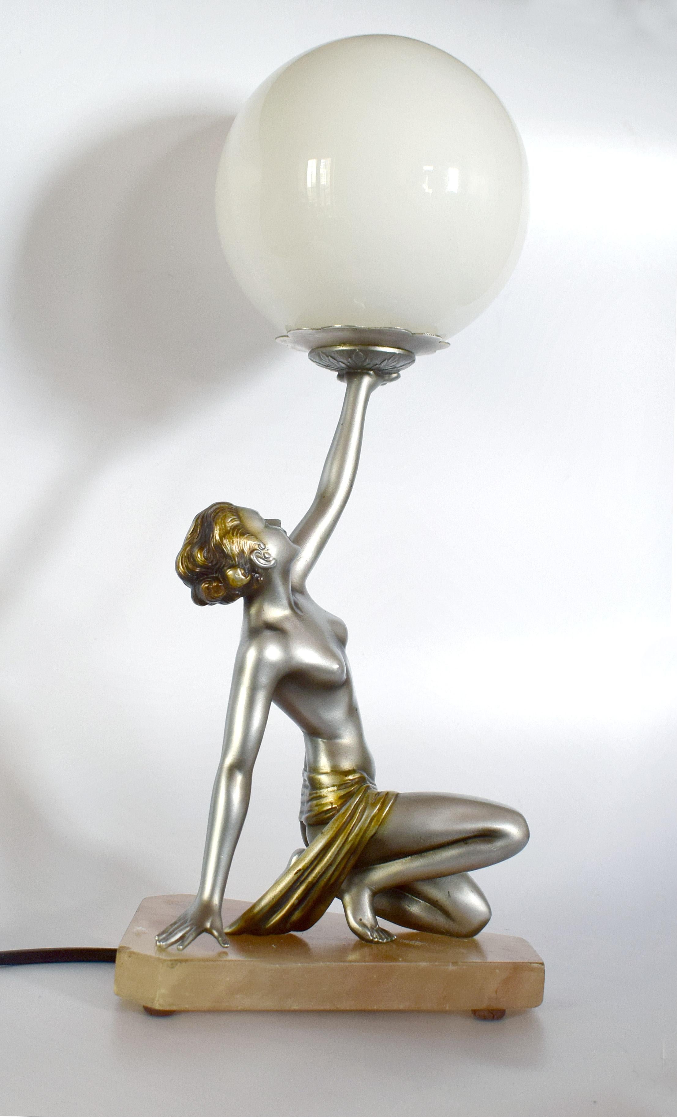 An impressive 40 cms tall this original 1930s Art Deco cold painted spelter table lamp is attributed to Lorenzl unsigned and features a semi nude lady holding aloft a milk white glass globe. Kneeling on an alabaster base she is in beautiful