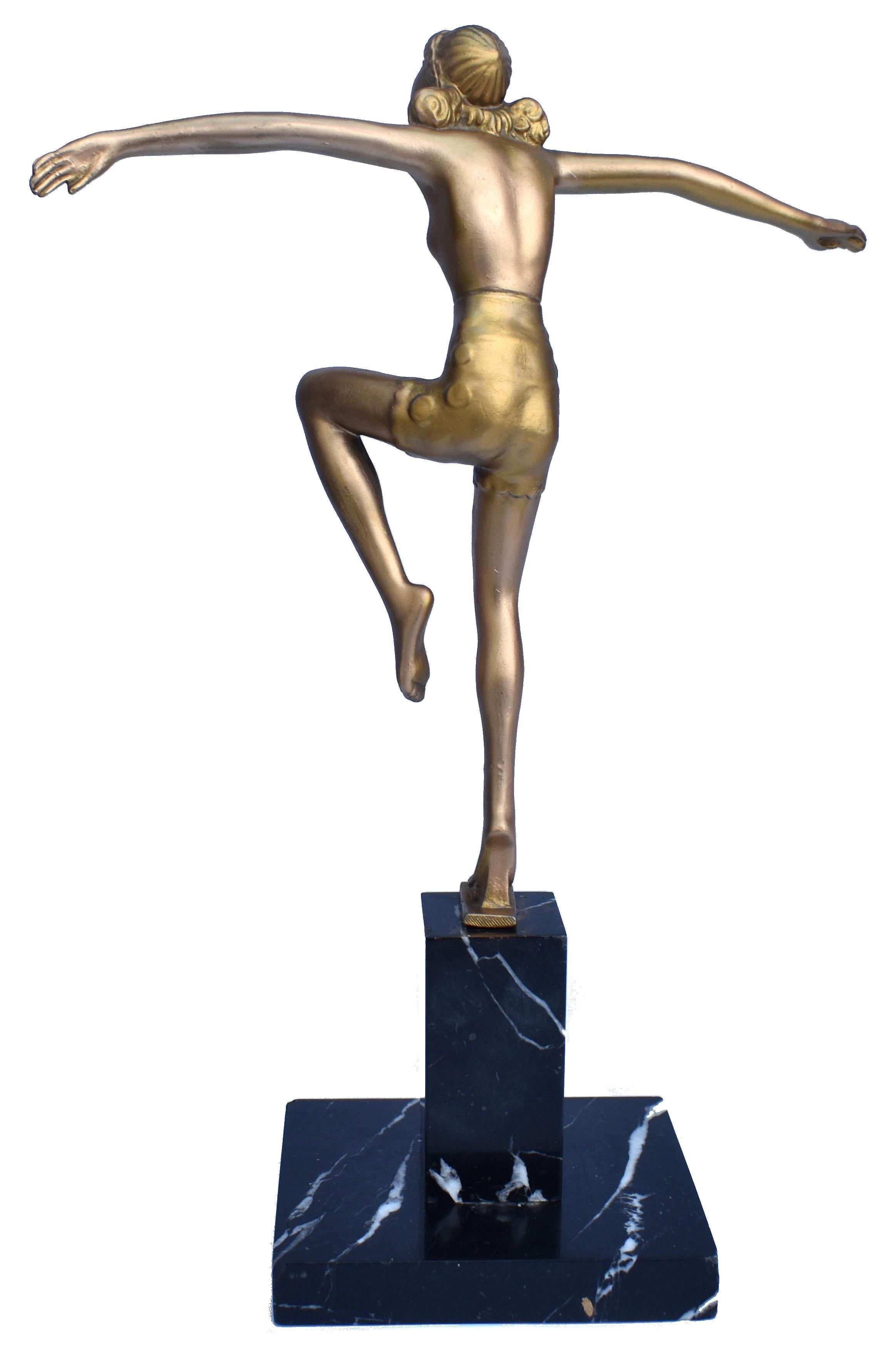Nice original example of Art Deco era patinated/painted spelter figurine of a semi-nude dancing girl. Slim gold-painted girl with wearing headdress and pink undershorts, very attractive, lively and innocent dancing pose. Two-part black veined marble