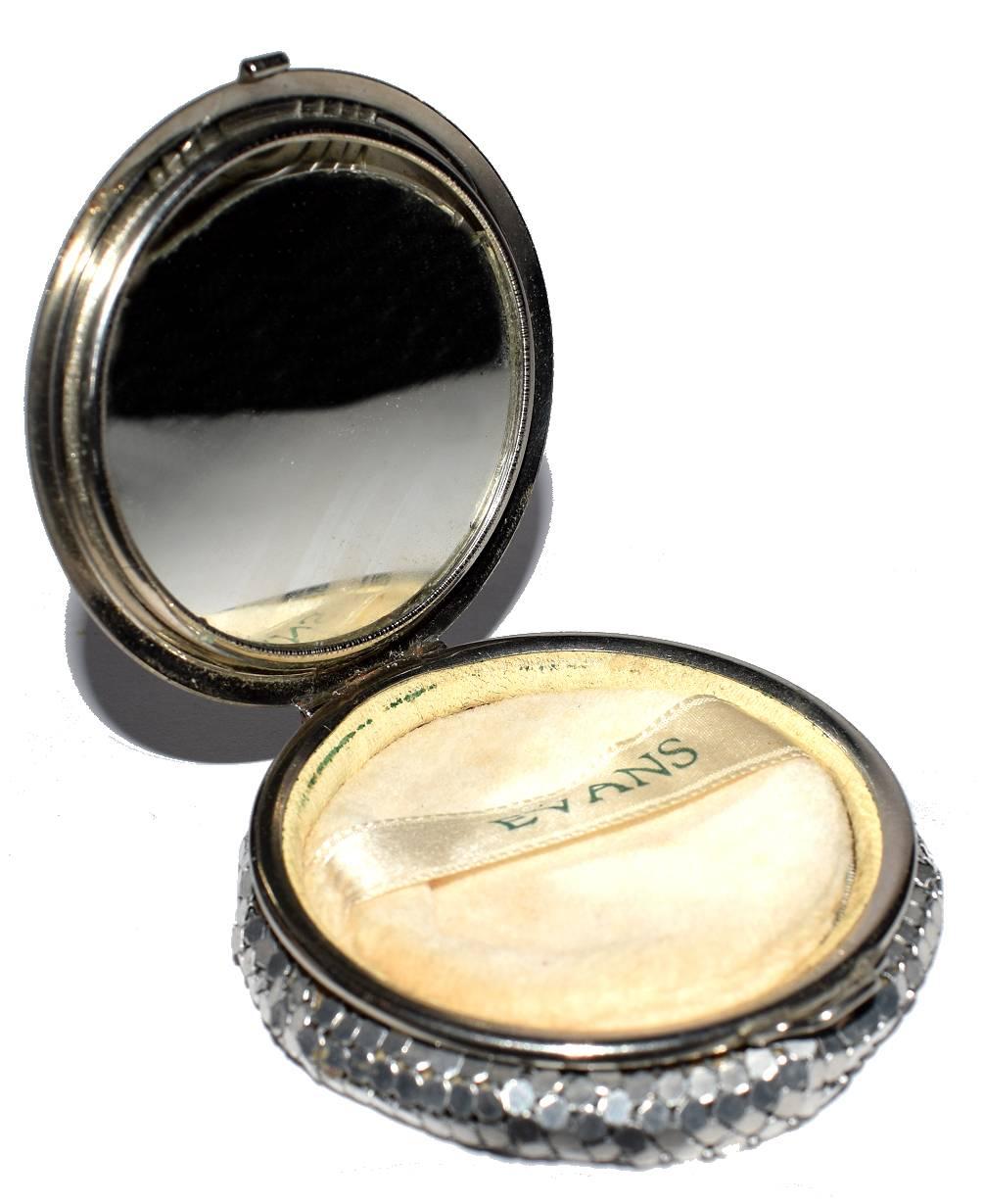 Original Art Deco vintage ladies powder compact by Evans. The lid cream enamel with a central embossed Art Deco design in chromed metal. The body of the compact is soft mesh and feels very soft to the touch. Condition is above average, the mirror is