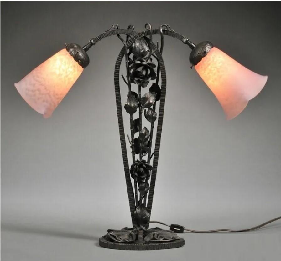 The Following Item we are offering is this Beautiful Rare Art Deco Wrought Iron and Schneider Glass Two-light Table Lamp. The central stem designed as a trellis training roses, with ombre purple glass shades overhanging on either side, on oval base