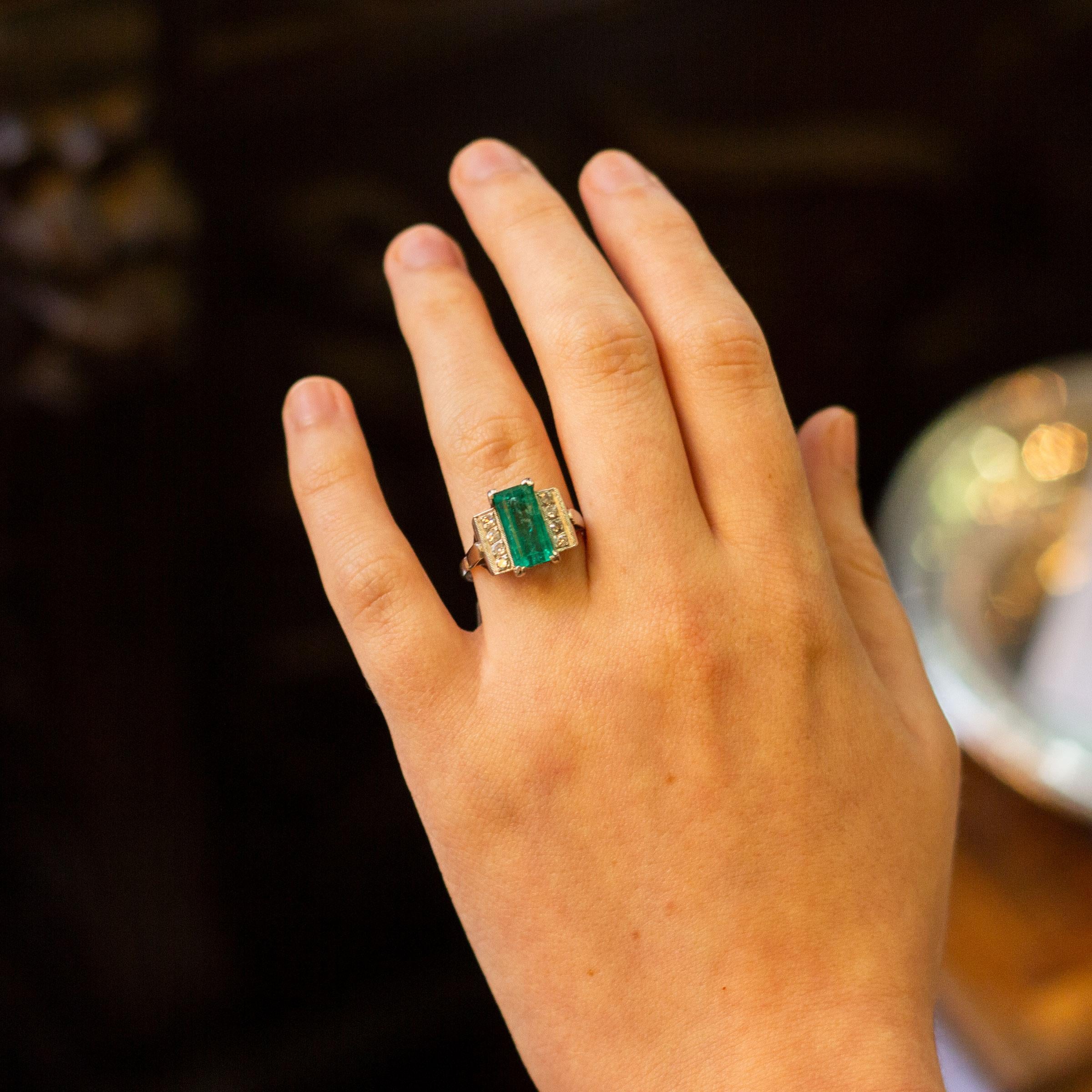 A striking platinum, diamond and Columbian emerald ring from the 1930s. The ring is entirely handmade from platinum and features to the centre a four claw set octagonal cut good green Columbian emerald weighing 2.75 carat. On each shoulder of this