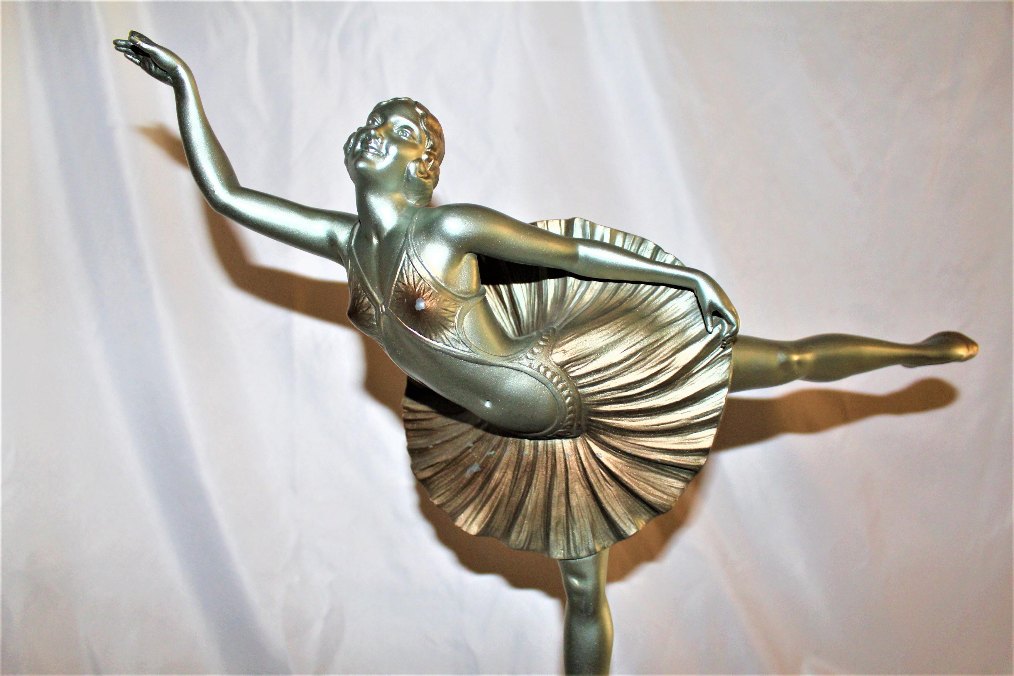A good size deco figurine of a ballerina standing on one foot. Has part of one finger missing. Measures: Height at 20 3/4