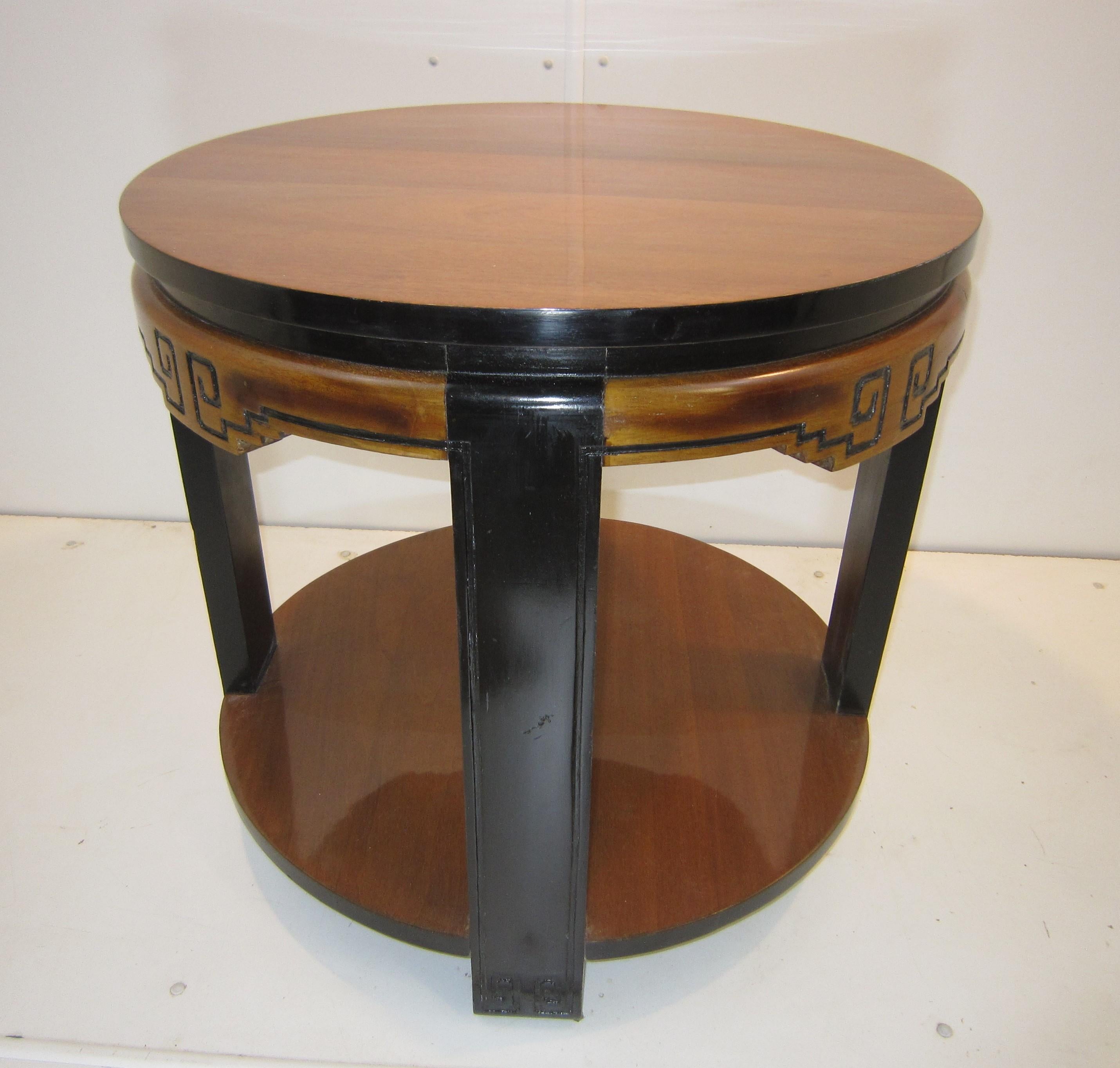 Fine French Art Deco circular table of chinoiserie design, highly sculptural and two tone in walnut with ebonized accents.
The circular top surrounded by a bull nose hand carved molding featuring a stylized Greek key design.
The whole mounted on
