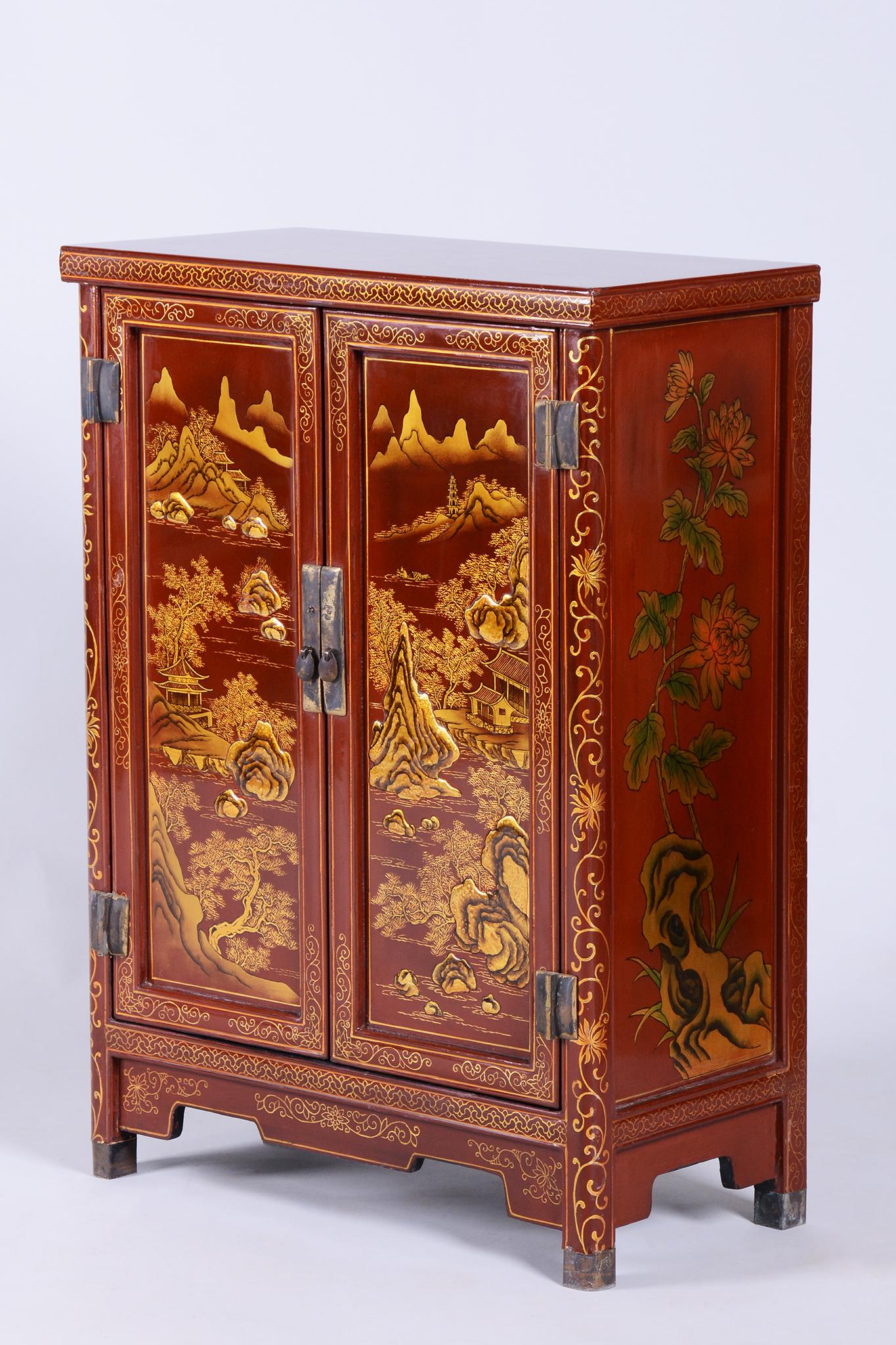 This charming Asian-style cabinet originates from China and dates back to the mid-19th century. It is crafted from lacquered and painted wood, adorned with rich ornaments and colors typical of Chinese artistry. The cabinet has been preserved in very