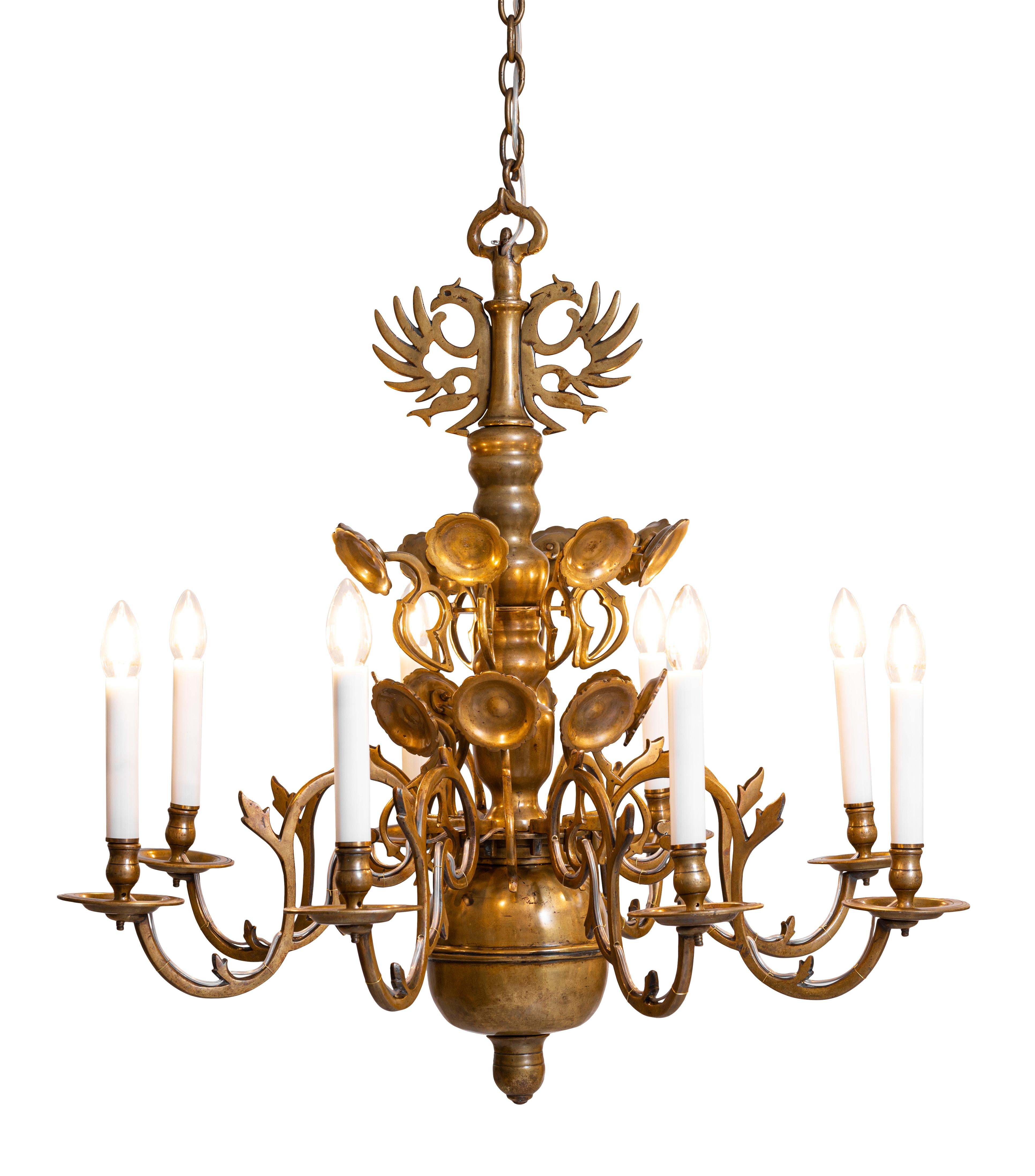 Polish baroque chandelier from the 18th century, originally for wax candles, electrified end of 19th century. Brass-body in baluster-form with pluged in blossoms, voluted arms and eagletop. Please notice the handcut screws and the varied casting and