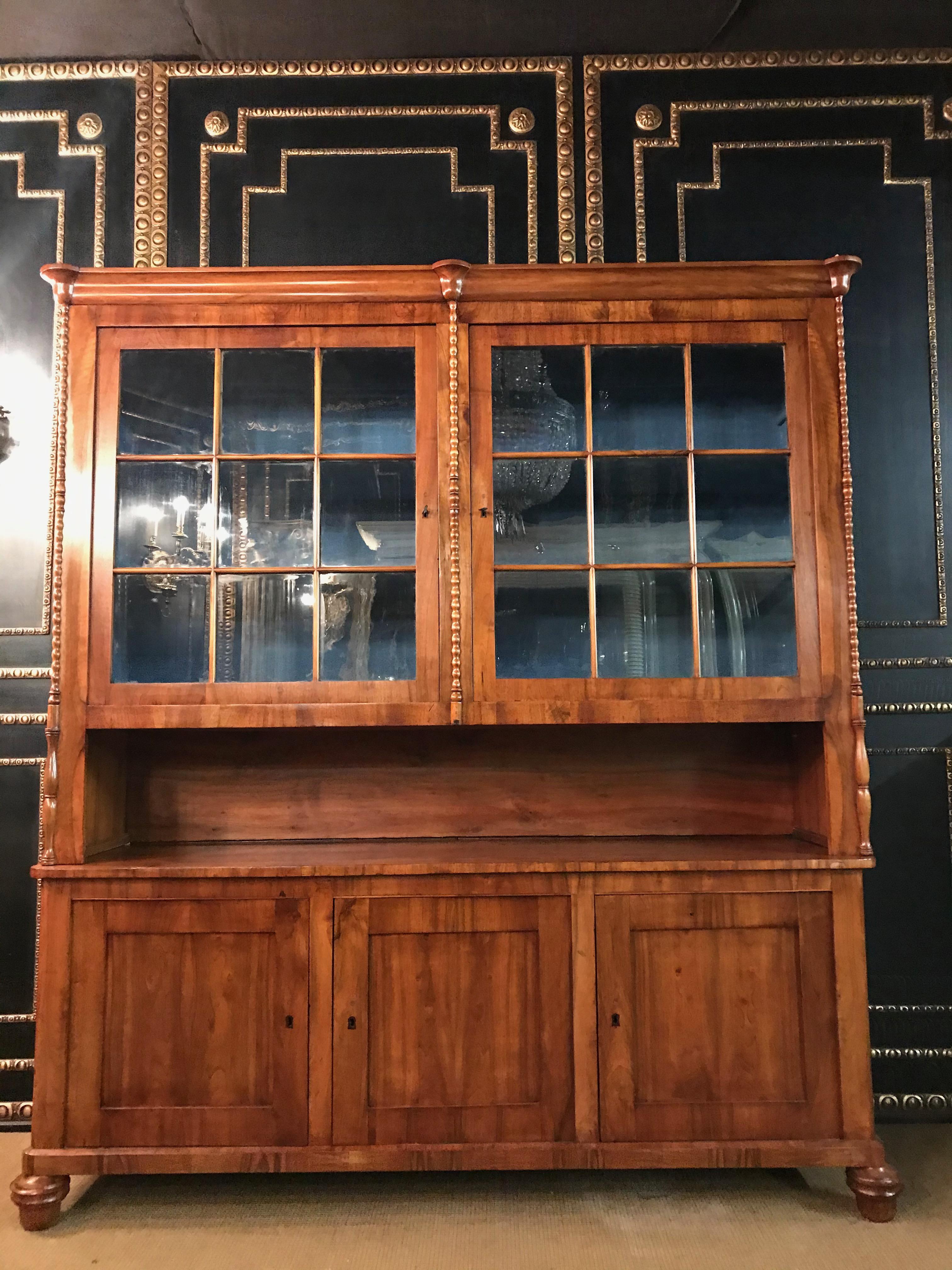 Large original Biedermeier library, light walnut, circa 1840.
 
The library consists of a closed base with three doors and a glazed top with two large doors.

The top has two doors, six crystal glass panes are inserted into each of the cutouts
