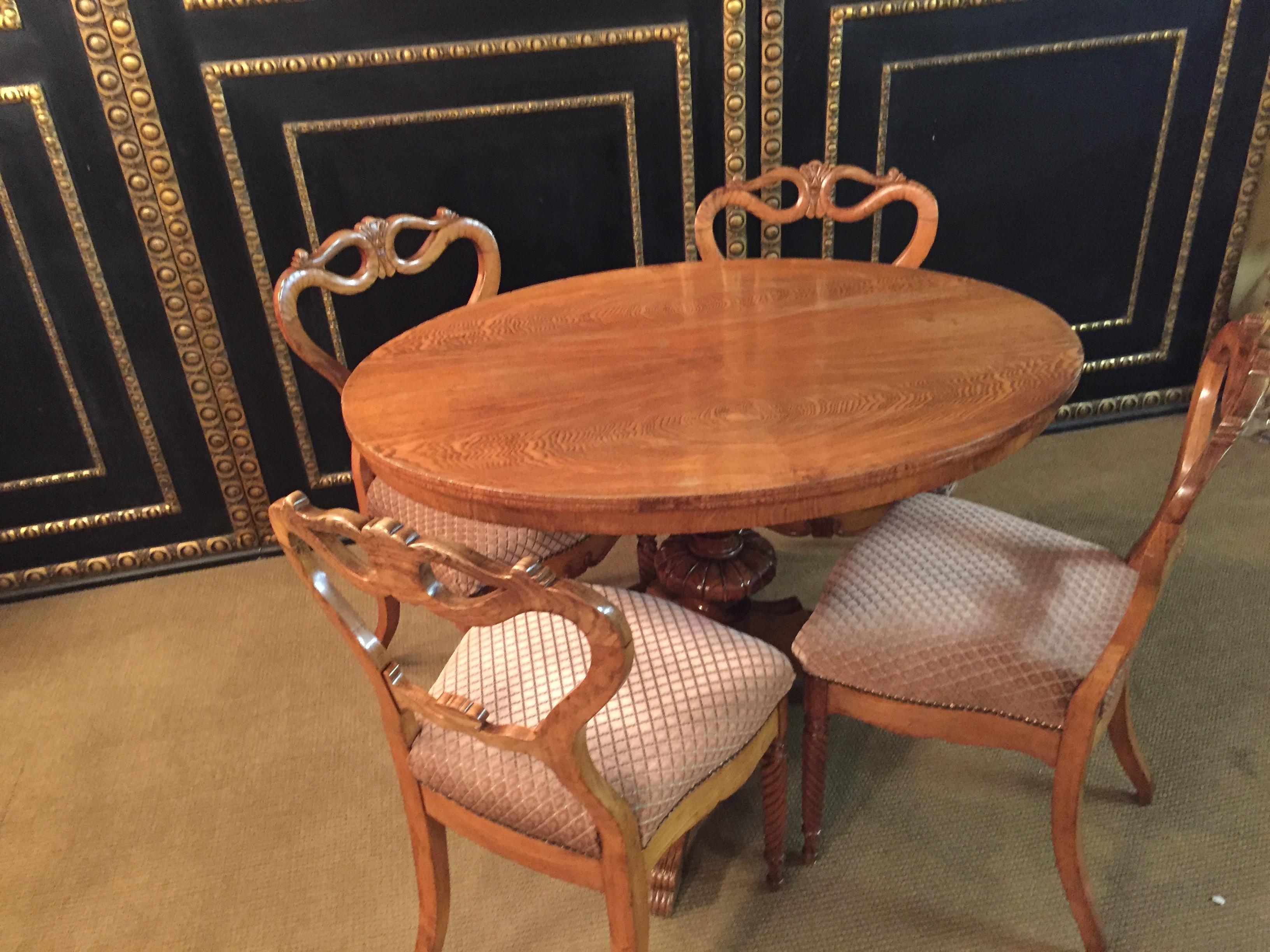 Beautiful dining table with 4 chairs original Biedermeier Ashwood,  around 1850.
Turned table with center column with 3 legs end in paw feet end.
Chairs at the front, the legs turned and curved at the back.
Backrest with beautiful ornaments.