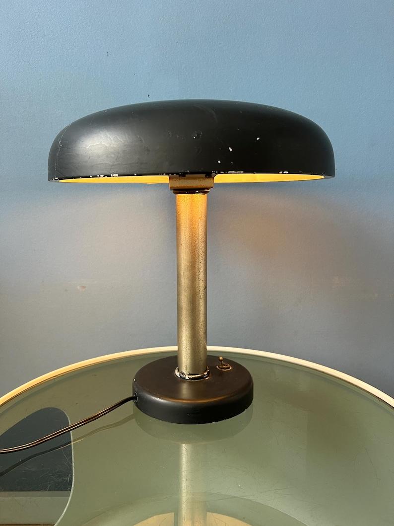 Preciosa lámpara de mesa bauhaus negra original de los años 30. La lámpara tiene un aspecto robusto. La lámpara es totalmente de metal y está lacada en negro. La lámpara de escritorio requiere una bombilla E27/26 y actualmente tiene un enchufe