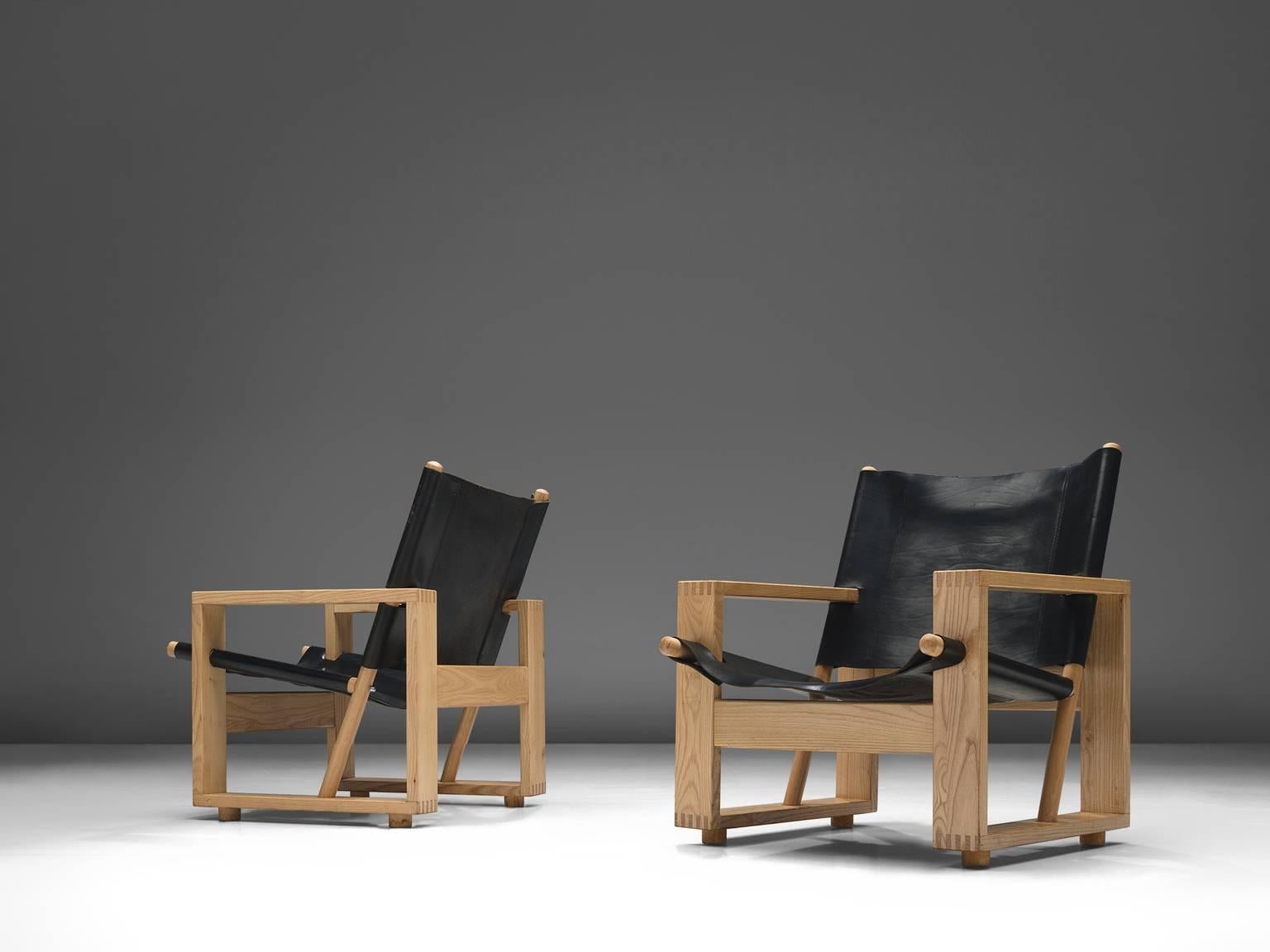 Lounge chairs, black leather and ash, Europe, 1970s.

These sturdy, strong chairs are executed in ash and black leather. The chair is large in both its appearance and seating space. The armrests are executed in ash and have rounded details for the