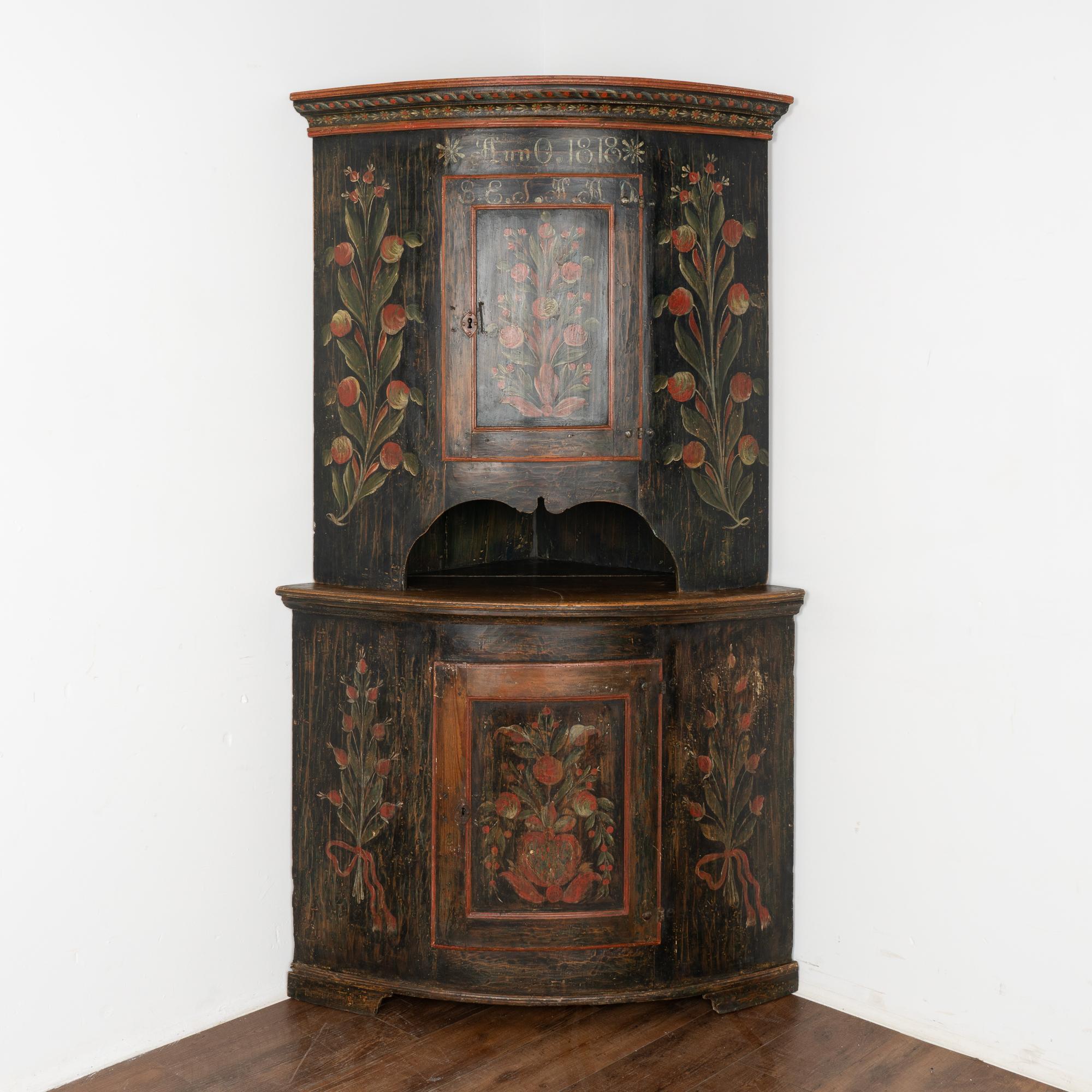 This stunning pine corner cabinet still maintains its original black painted finish with traditional floral details along panels and crown.
The monogram and date of 1818 indicate it was likely a very special wedding present.
This corner cupboard is