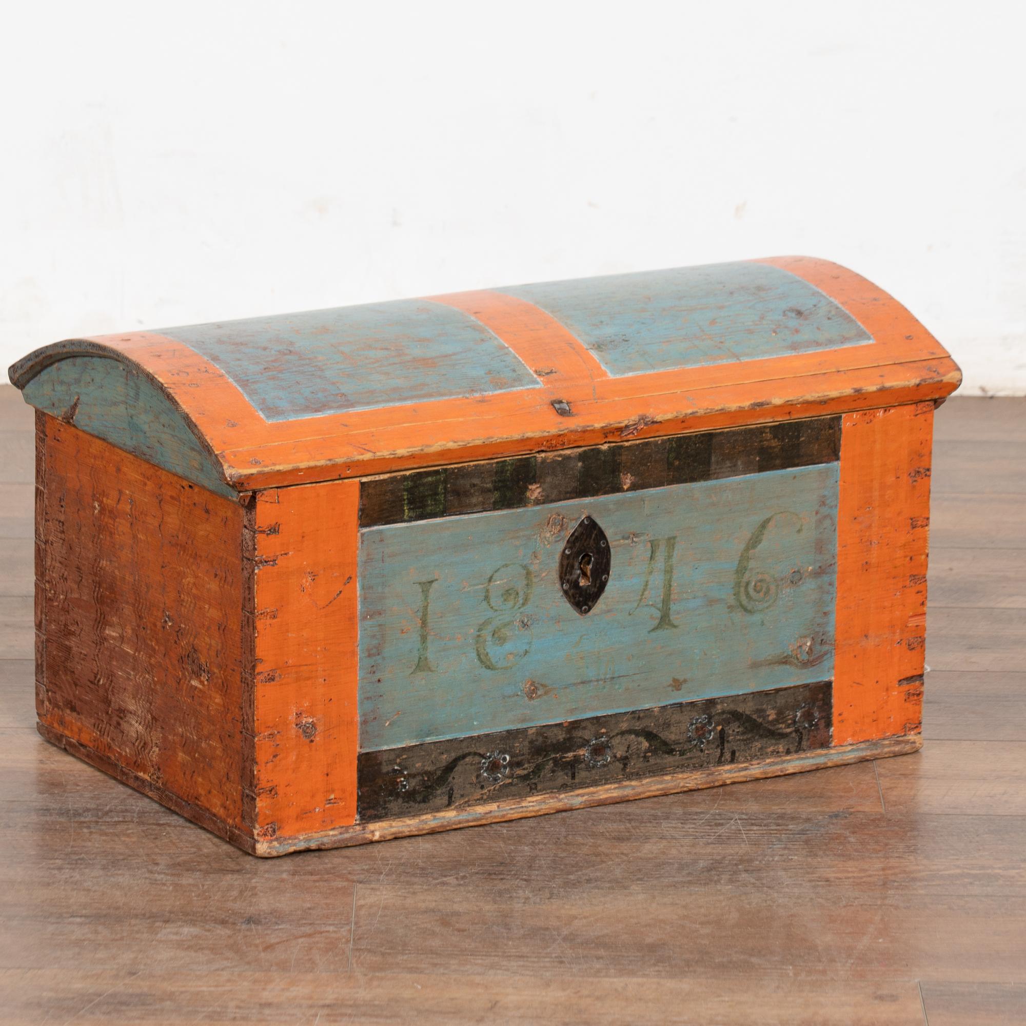 Piccolo baule a cupola proveniente dalla Svezia e datato 1846.  Lo sfondo arancione brunito e gli accenti azzurri sono dipinti a mano nel tradizionale stile folk dell'epoca.
La patina consumata aggiunge un fascino senza età, mentre altri segni di
