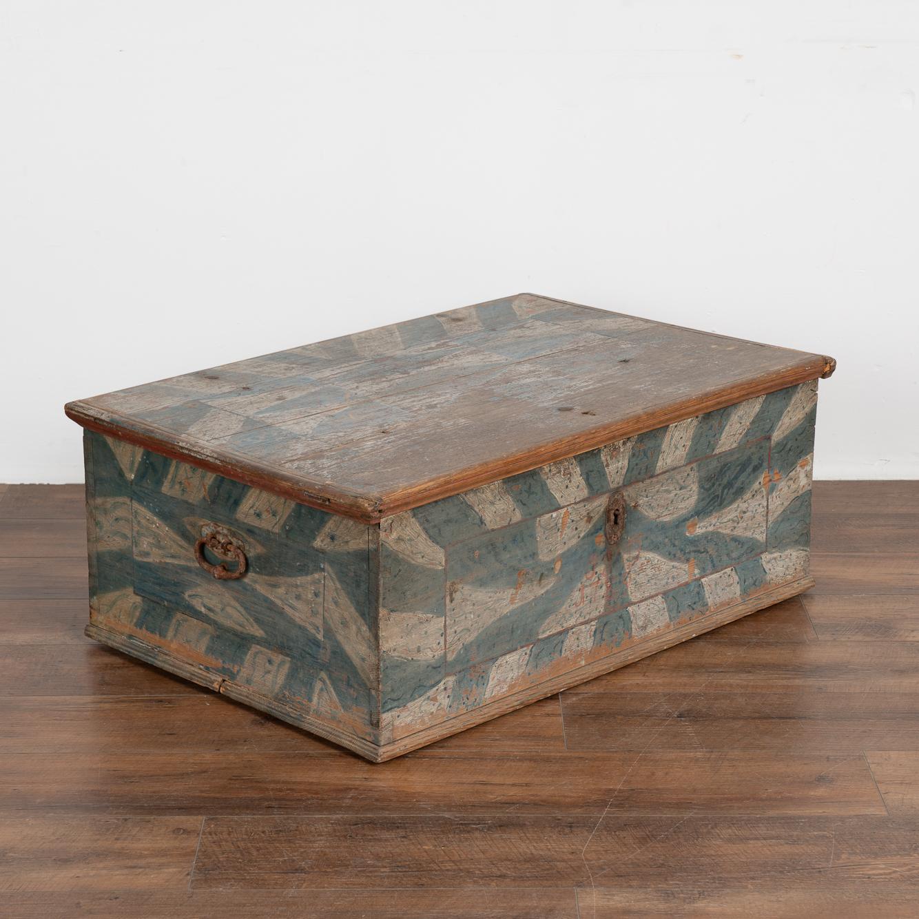 Generations of use are revealed in the distressed wear to the original blue and white folk art painted finish in this flat top pine trunk. Captured perfectly here, this highly sought after patina is always a special find, especially when dated