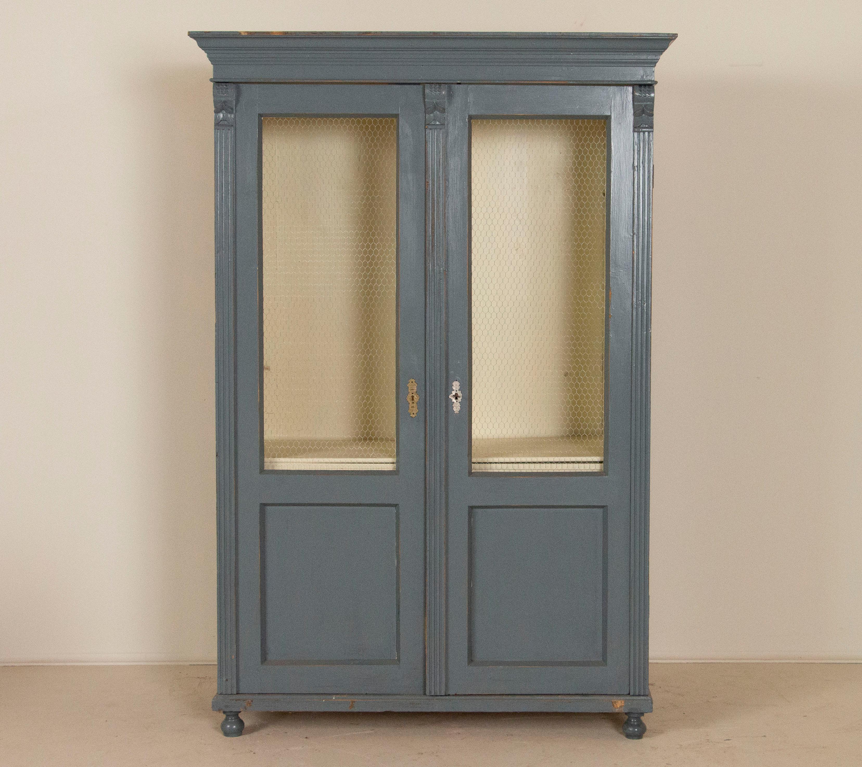 This antique blue painted Swedish 2-door bookcase has had the glass replaced with wire mesh giving the bookcase a more open and accessible feel. Where the deep grayish blue paint has been scraped there are hints of natural pine showing through