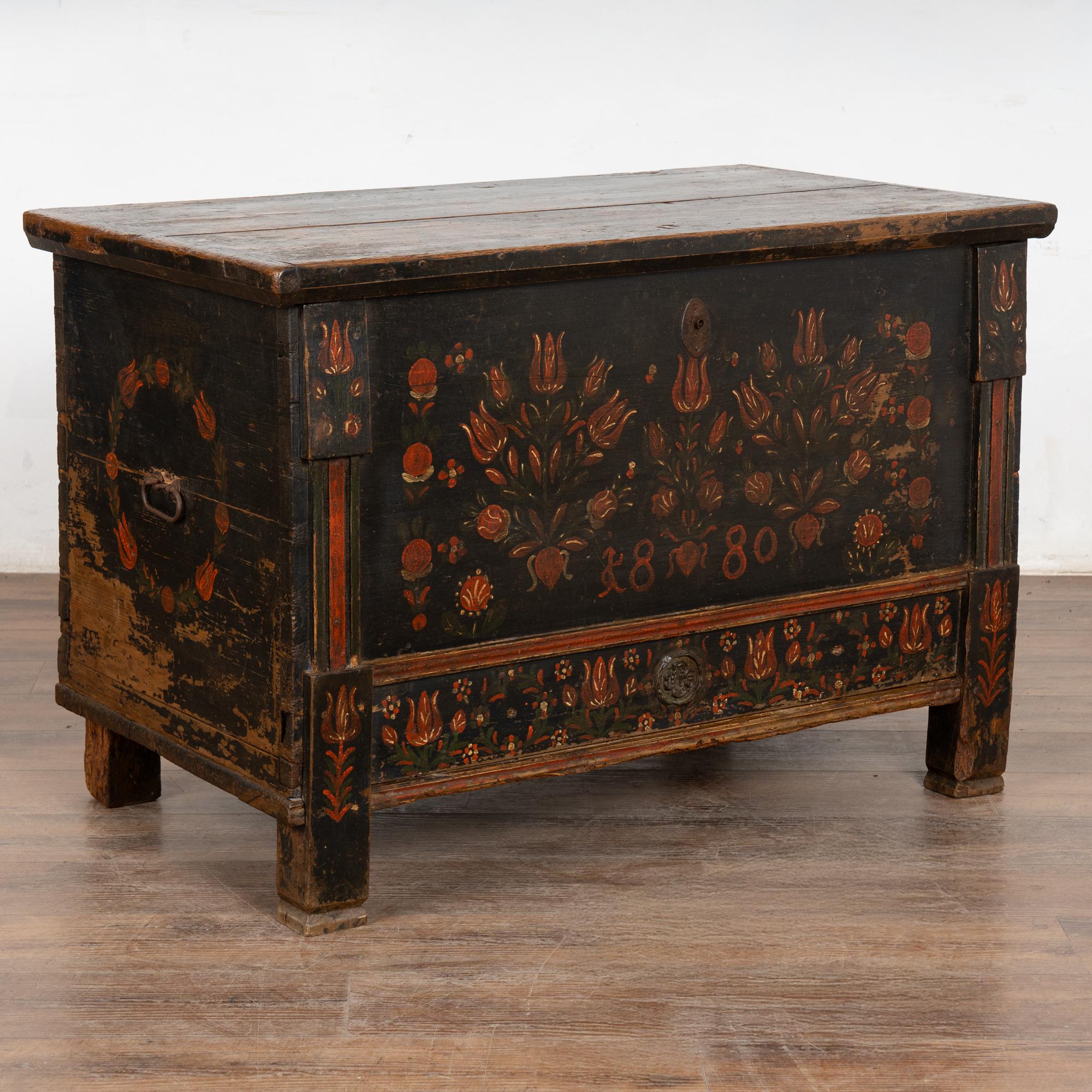 La finition peinte est entièrement d'origine sur ce coffre rustique en pin à dessus plat. Les fleurs étaient un ornement traditionnel, comme on peut le voir sur le devant de cette malle artisanale, où les fleurs rouges contrastent avec le fond bleu