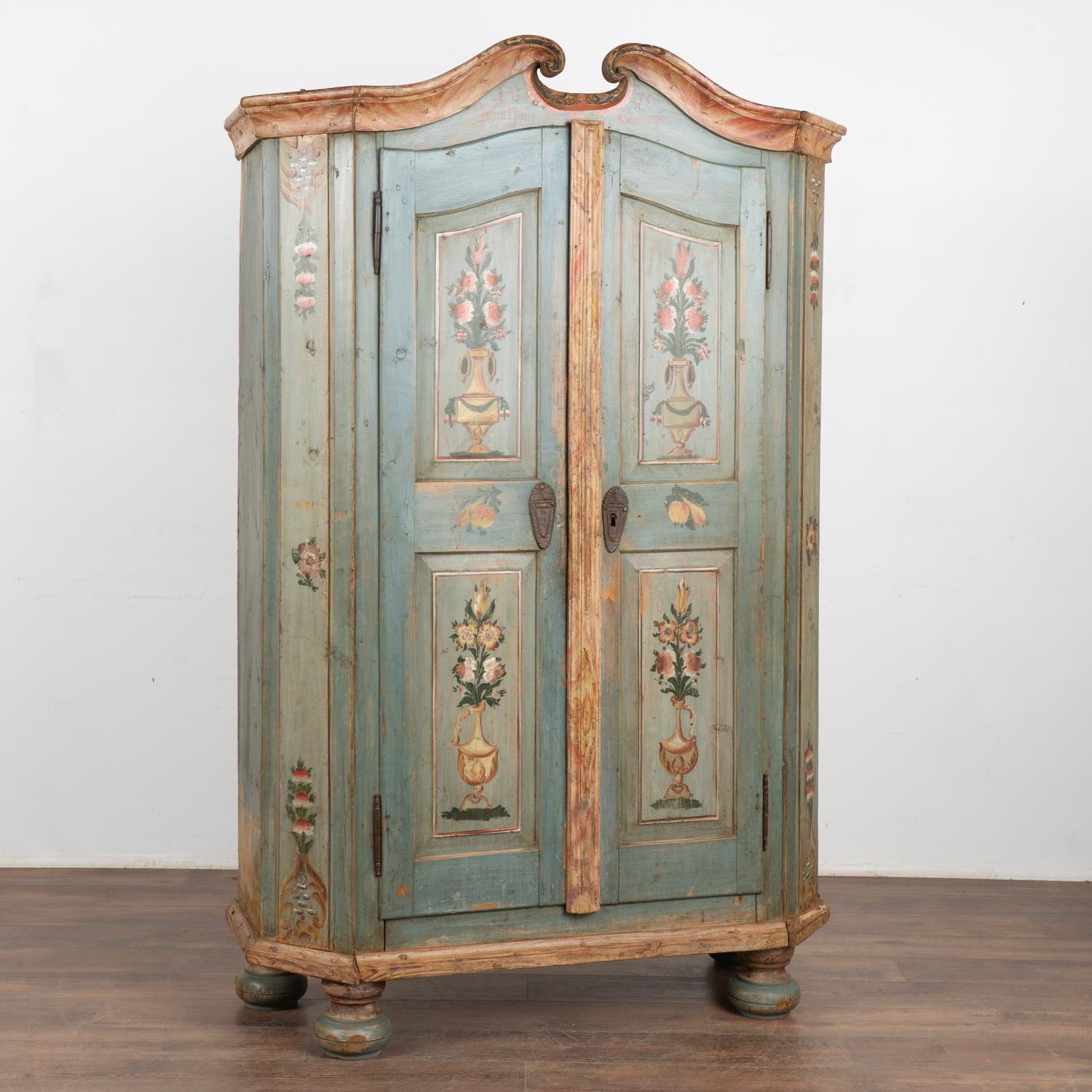 This delightful painted pine armoire still maintains the quality and details of the original hand-painted finish with background tones of soft blue and teal.
Note in the crown/bonnet the date of 1835 with names underneath.
Notice the 4 panels of