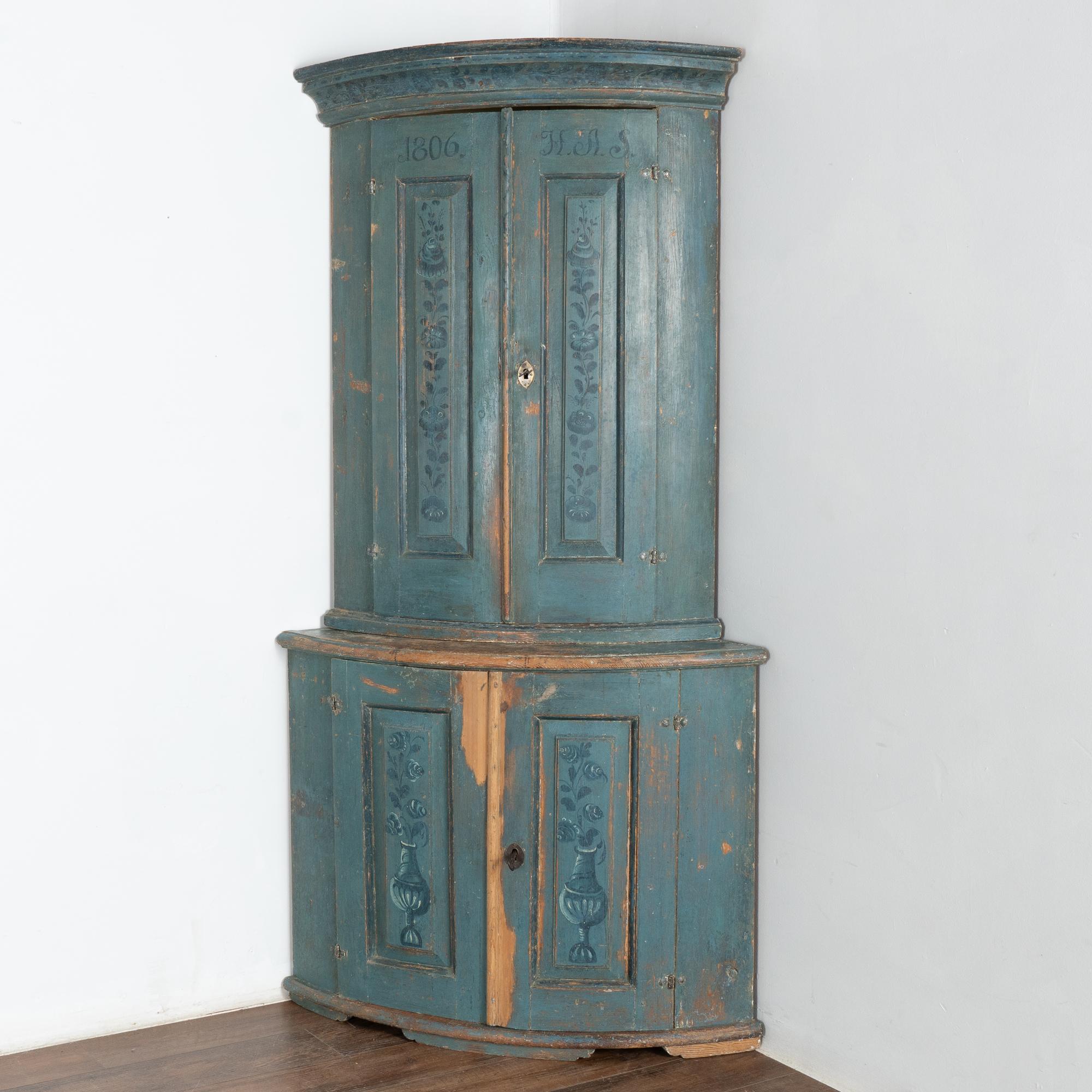 This bow front pine corner cabinet still maintains its original blue hand-painted finish with simple floral details remaining along the panels and upper molding.
The original blue painted finish (with teal undertone) has a soft, worn patina aged