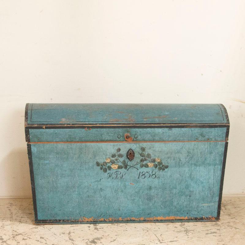 This endearing Swedish dome top trunk is embedded with a simple grace. The original blue painted finish with black trim is just exquisite, a perfectly aged patina that draws one to it. Lovely white roses wrap around the key hole, bringing attention