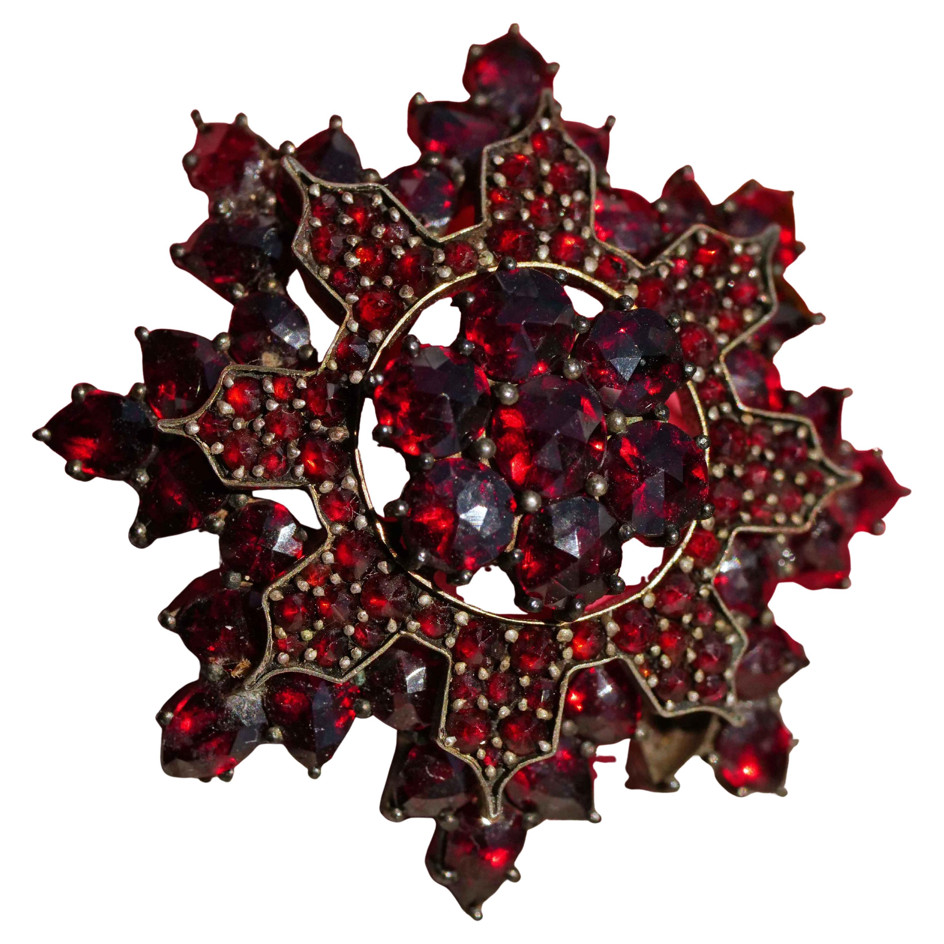 This fine brooch was made in Bohemia circa 1860-1890. The star design consists of different rows with numerous rose cut  faceted garnets which are clamped together. The brooch is set in a material called tombak with original carbuncle stones in a