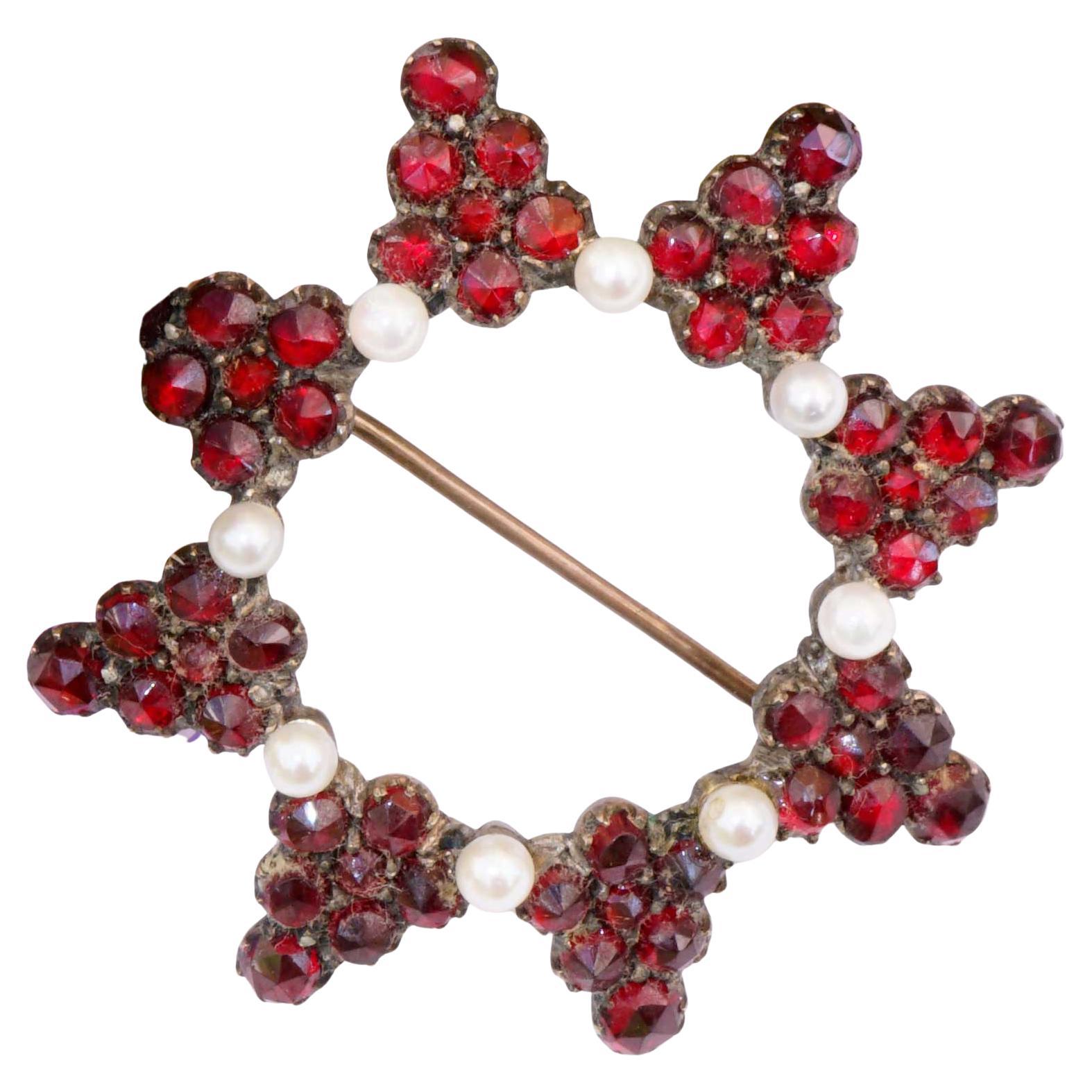 This fine brooche was made in Bohemia circa 1860-1890. The star design consists of different rows with numerous rose cut  faceted garnets and eight white fine cultured pearls. The brooche is set in a material, which is called tombak with original