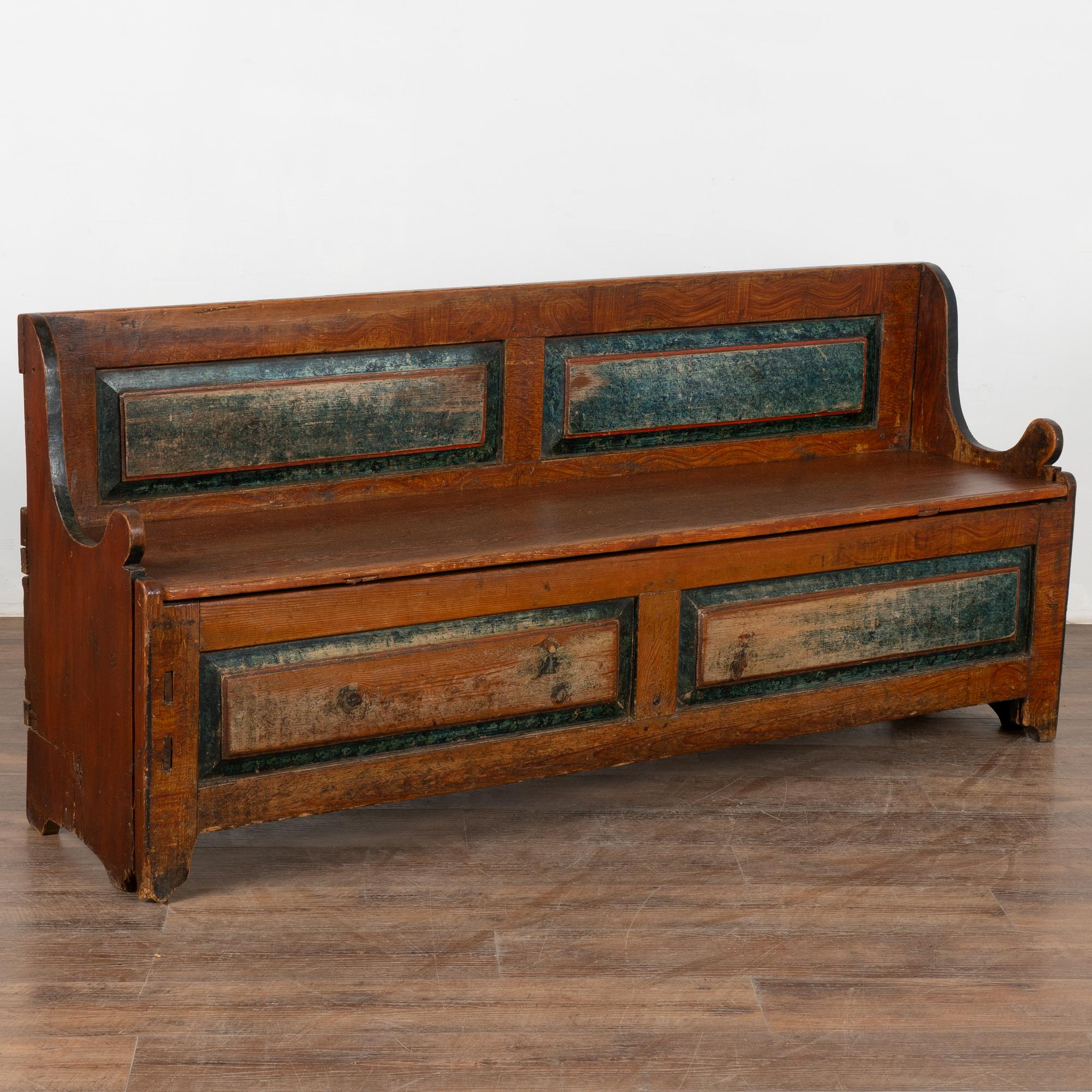 This original hand painted Swedish pine bench displays a brick red/brown faux wood background and simple blue folk art motif along the front and back panels.
The bench seat opens to reveal interior storage. Bottom section can be pulled forward as