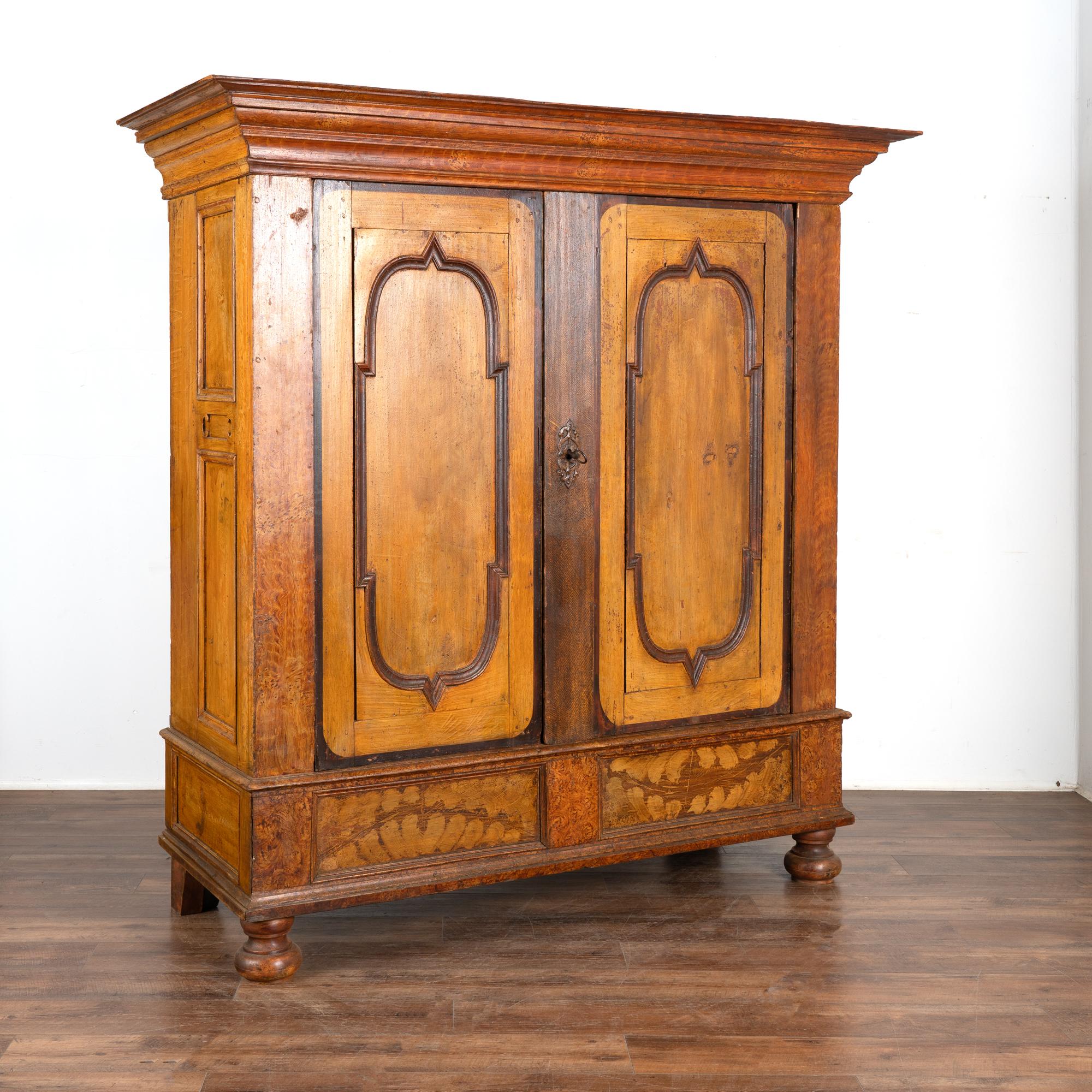 Take note of the exceptional original faux wood painted finish on this stately pine armoire which dates back to the late 1700's into early 1800's. 
Please examine the close up photos to appreciate the warm colors, texture and patina of this