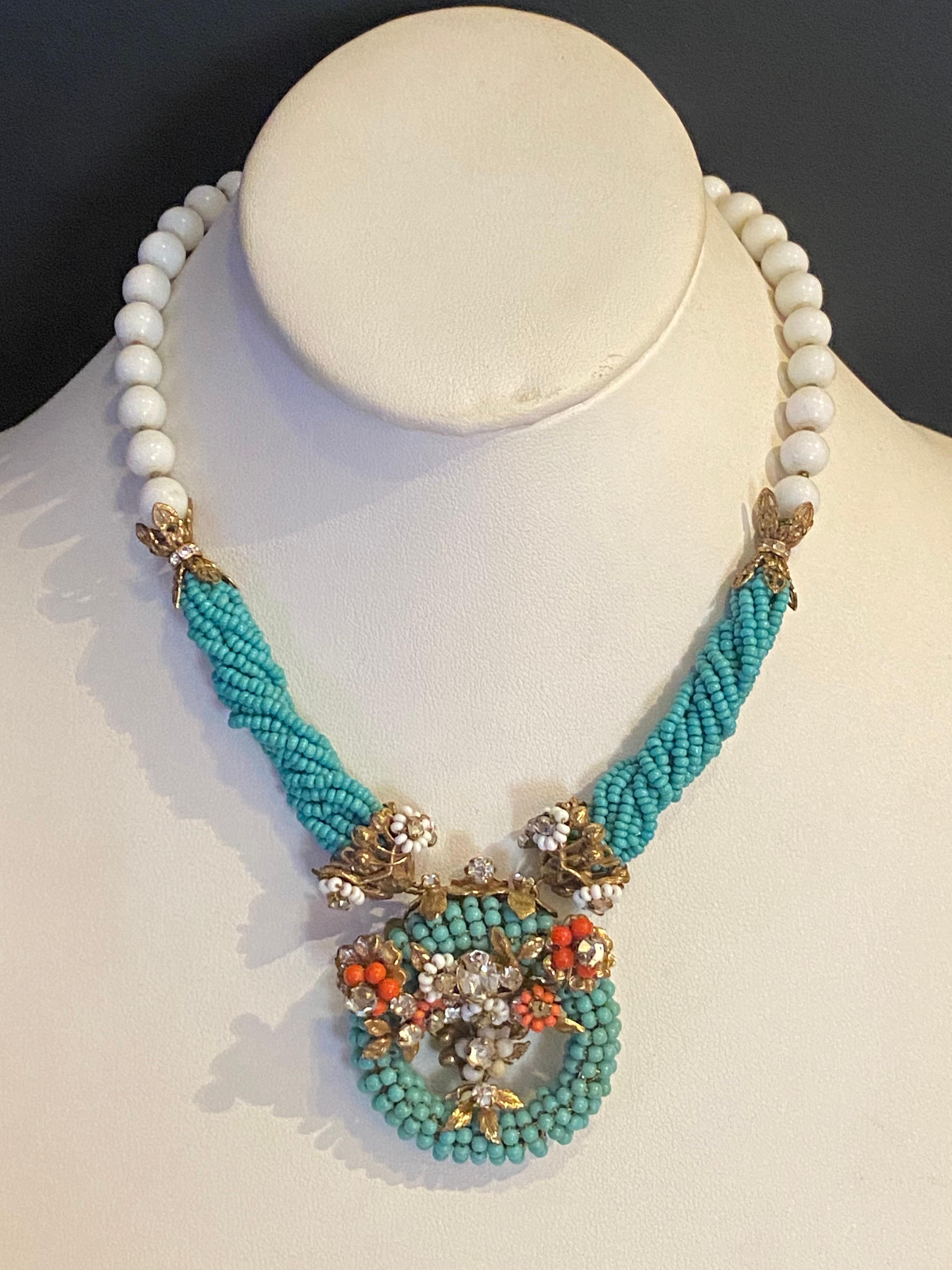 This beautiful hand made set features a stunning combination of turquoise, coral, and white glass seed beads. The necklace is designed with wrapped and twisted stands of turquoise glass seed beads, large  white glass beads, accents of coral glass