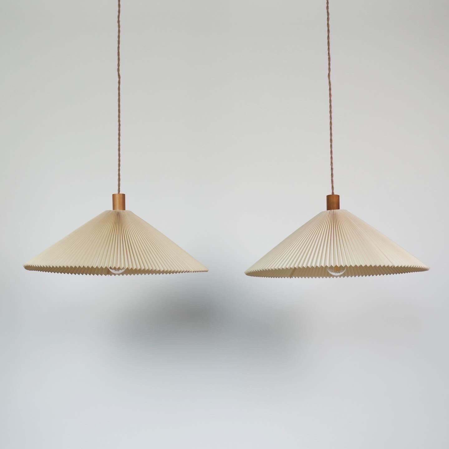 Raro set di lampade a sospensione originali Caprani realizzate da Mads Caprani negli anni Ottanta. 

* Set (2) di lampade a sospensione plissettate di colore bianco sporco con piano in legno.
* Designer: Mads Caprani
* Produttore: Caprani Light AS
