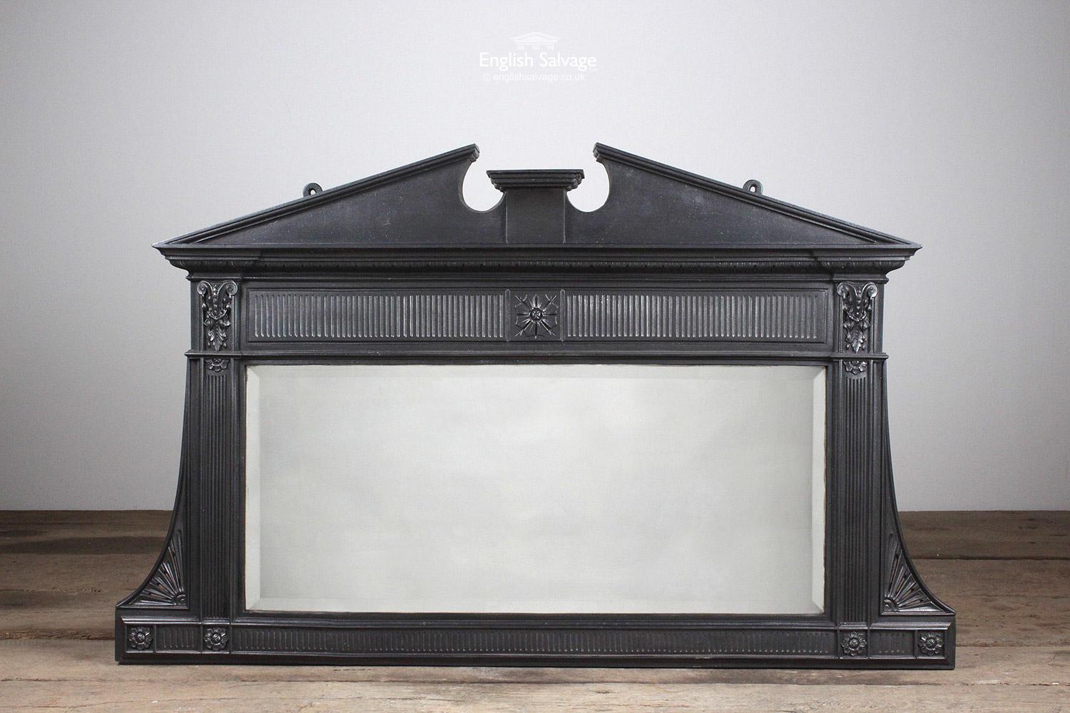 Vintage cast iron over mantel with a rectangular bevelled mirror, fluted and flower detailing, crowned with a broken style pediment. There are two holes for fixing and the over mantel is in good condition; there are no obvious breaks.