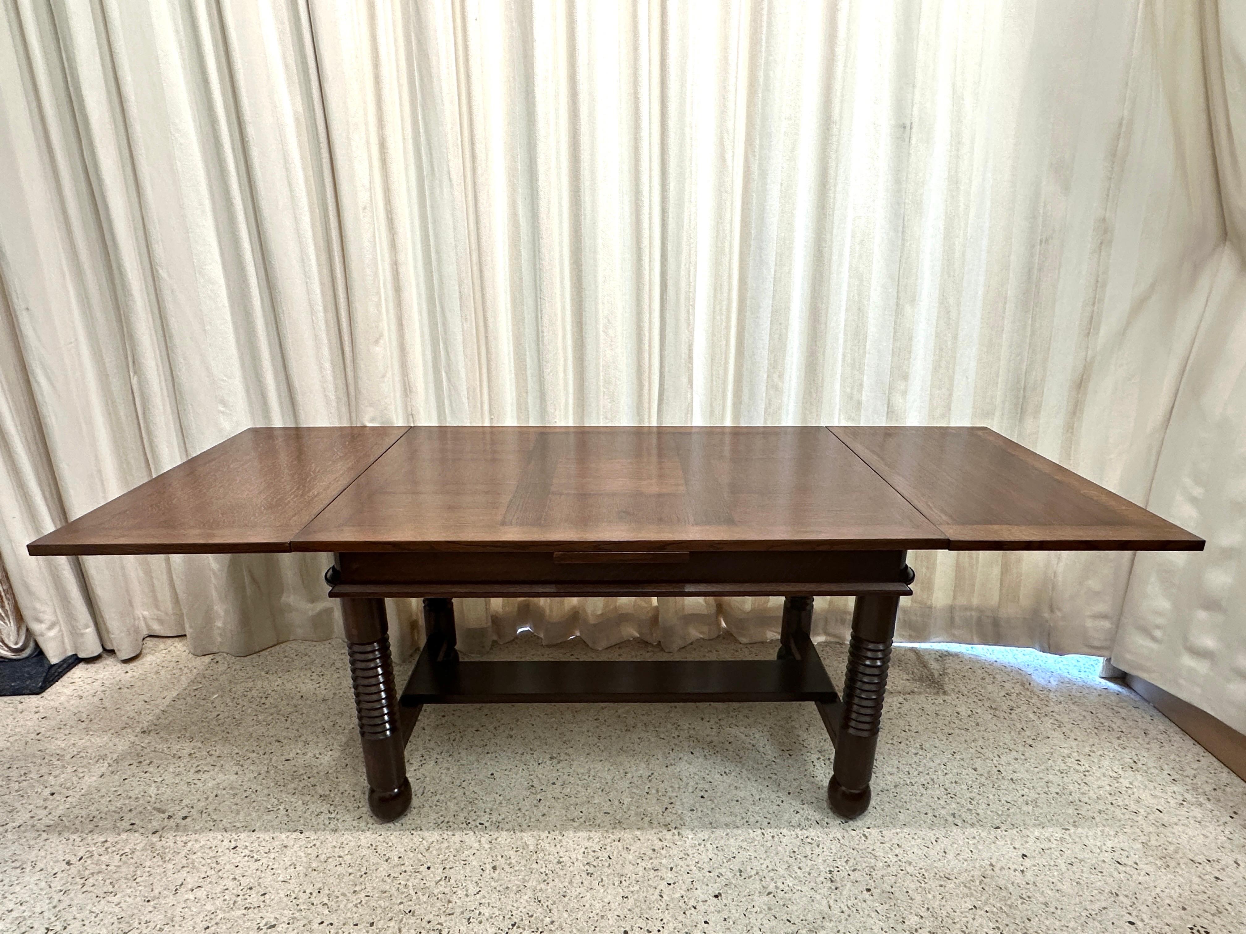 Original Vintage Art Deco Design Extendable Dining Table by Charles Dudouyt in a rich chocolate tone.  Made in France, 1940's. Solid oak constructed dining table with architecturally formed turned legs.  Exquisite marquetry table top and 2