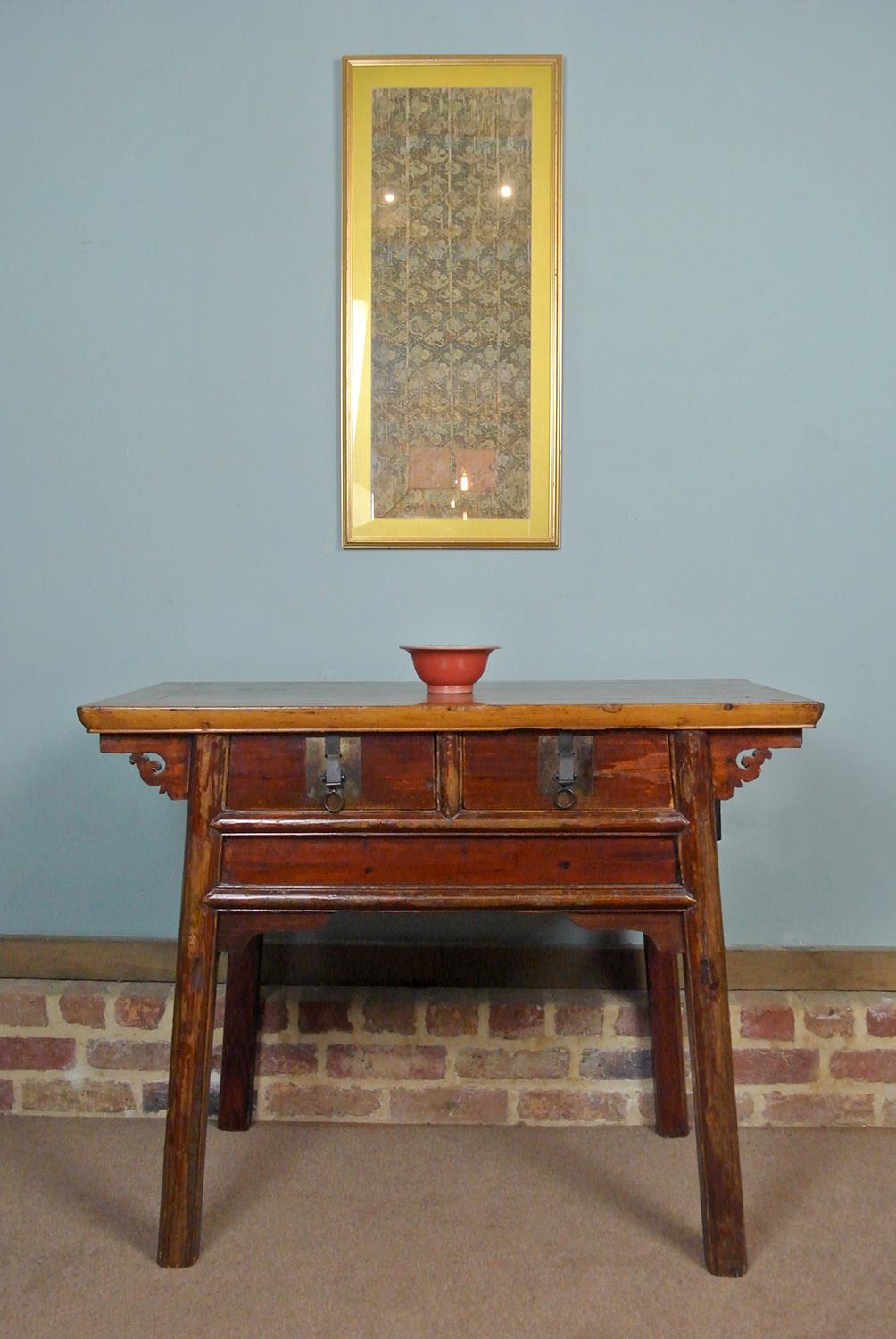 With a well developed rich and warm colour to the elm, this small and original 19th Century Chinese Elm altar table has a boarded, cleated and oversailing top over two front frieze drawers and retains the original bronze drawer pulls (with sliding