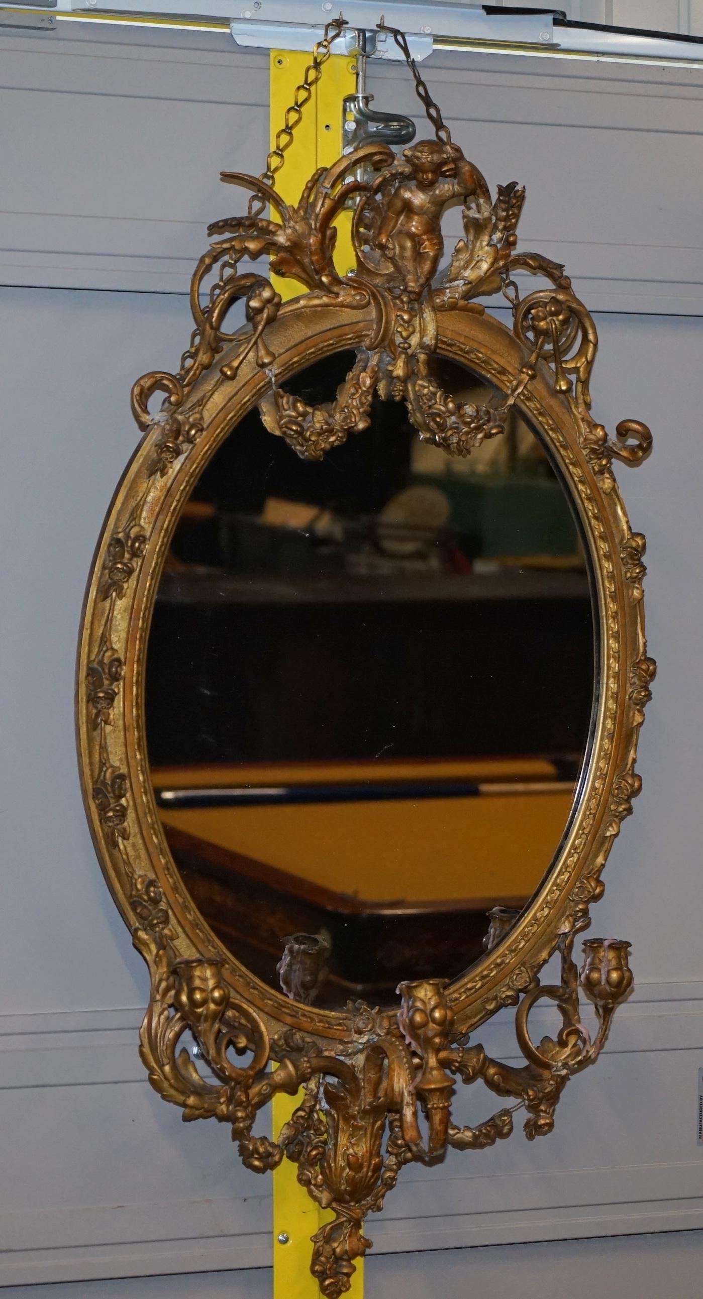 Nous sommes ravis de vous présenter ce très rare miroir Girandole datant d'environ 1800, encadré d'or et de dorure, avec son verre au mercure d'origine légèrement usé

Une trouvaille très rare, je n'en ai jamais vu d'autre avec un Putti sur le