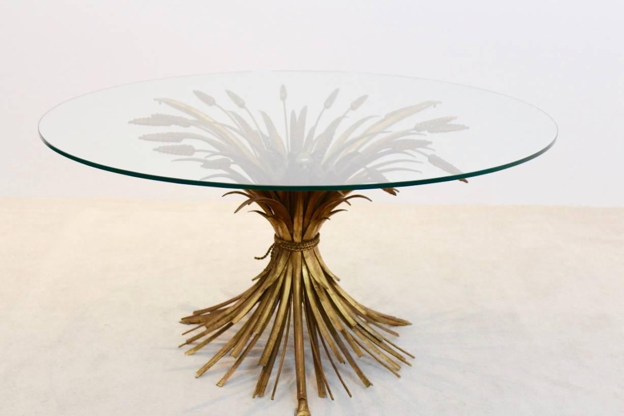 A truly eye-catching original gold-plated gilt metal coffee table. Fashioned in the shape of a wheat sheaf bound by string and a perfect round glass top. This table is a really old piece in original shape with the perfect height to be used as a wine