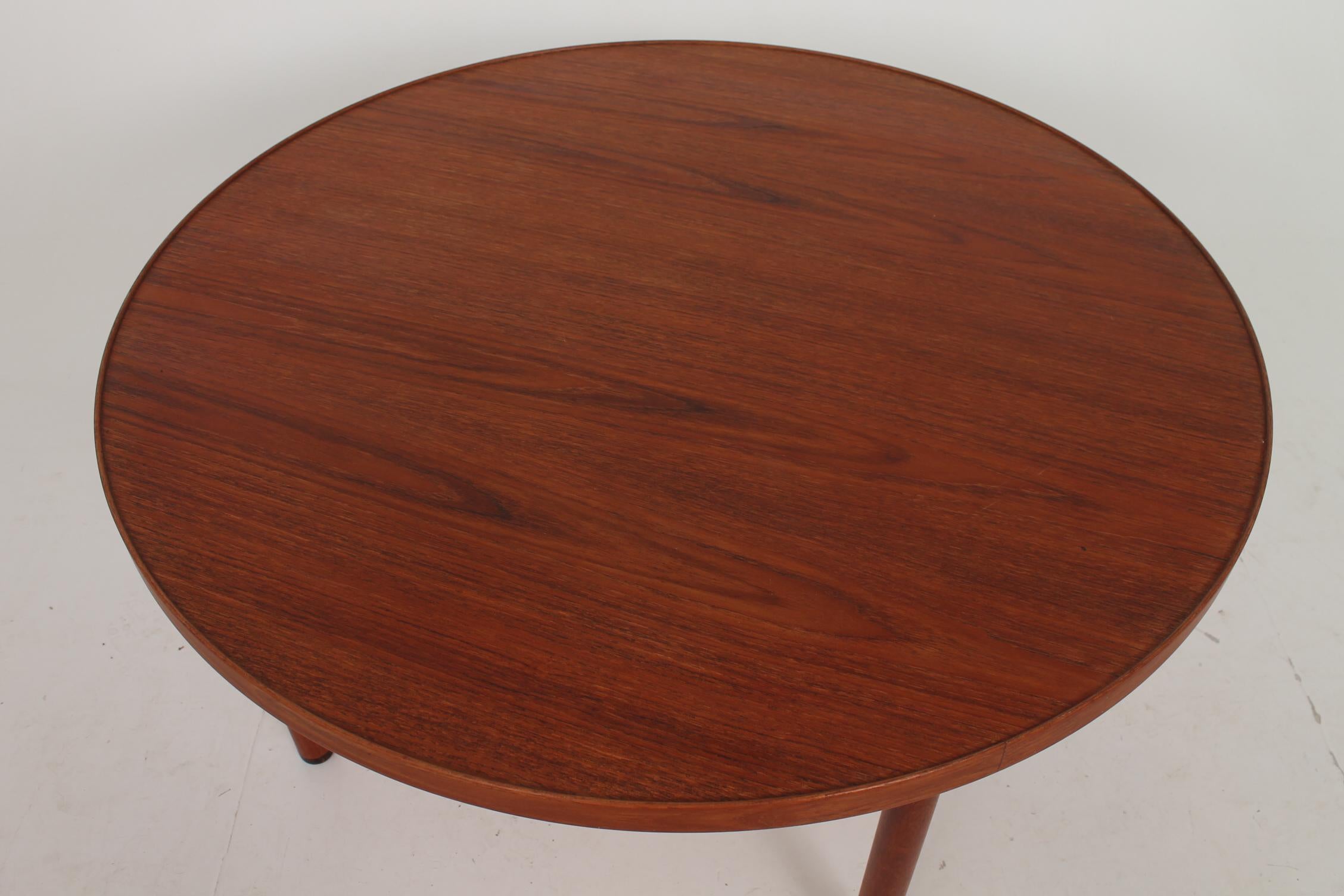 Round coffee table in teak with wengé shoes. Table top with a subtile edge as an outline. Stamped and manufactured by Næstved Møbelfabrik in the mid 1950s. Iconic design by Ejnar Larsen and Aksel Bender Madsen, Denmark. Condition is beautiful,
